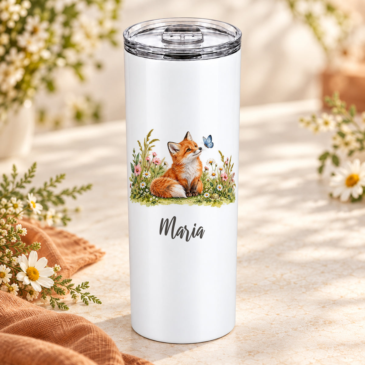 Weißer Thermobecher mit Fuchs-Aquarellmotiv und Wunschname auf einem Tisch mit Wildblumen und Leinen.