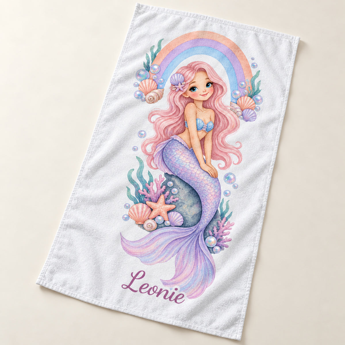 Handtuch mit Motiv Regenbogenbucht und Beispielname Leonie, schräg von oben gezeigt.