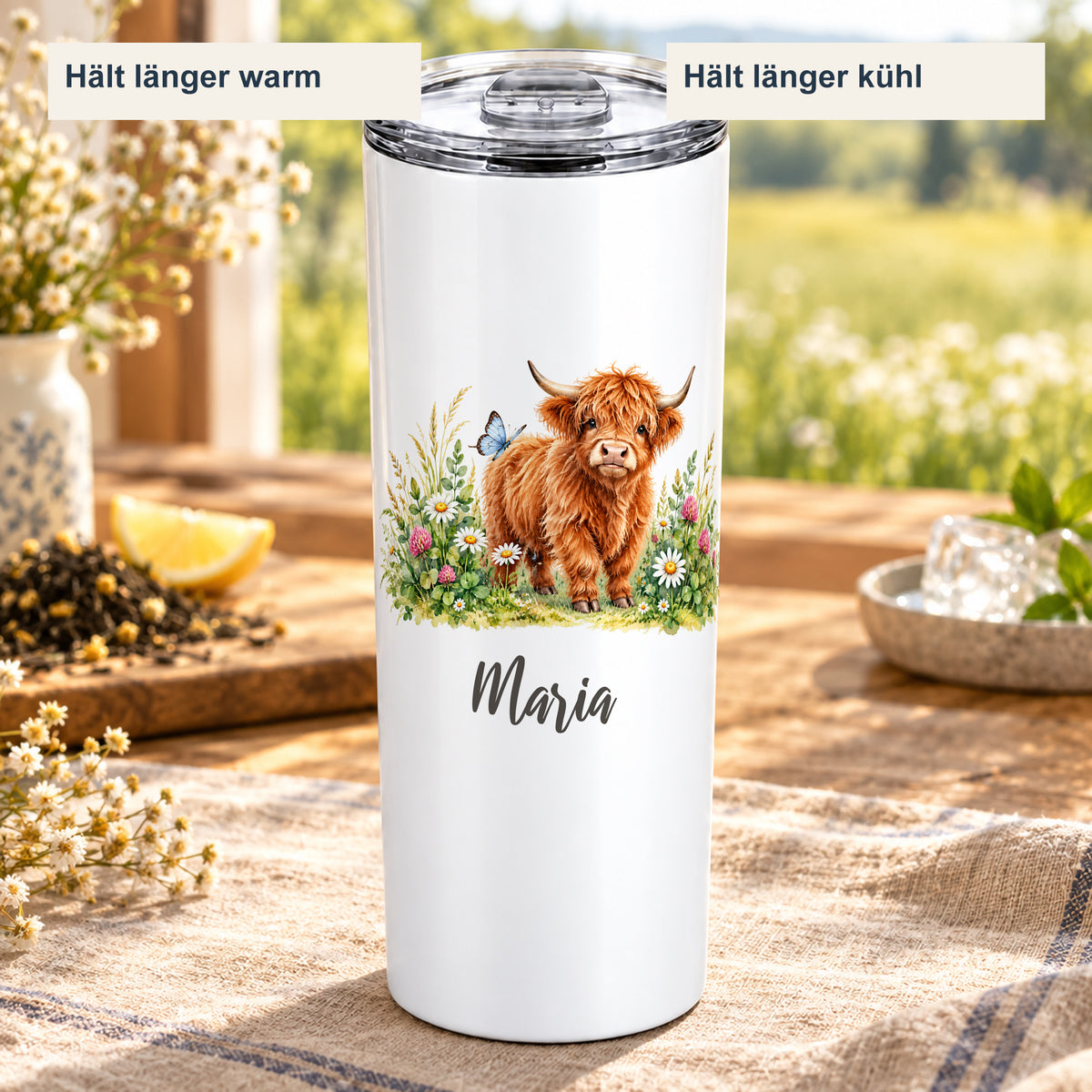 Thermobecher mit Hochlandrind-Motiv in einer sommerlichen Getränkeszene mit Hinweisen auf länger warme und länger kühle Getränke.