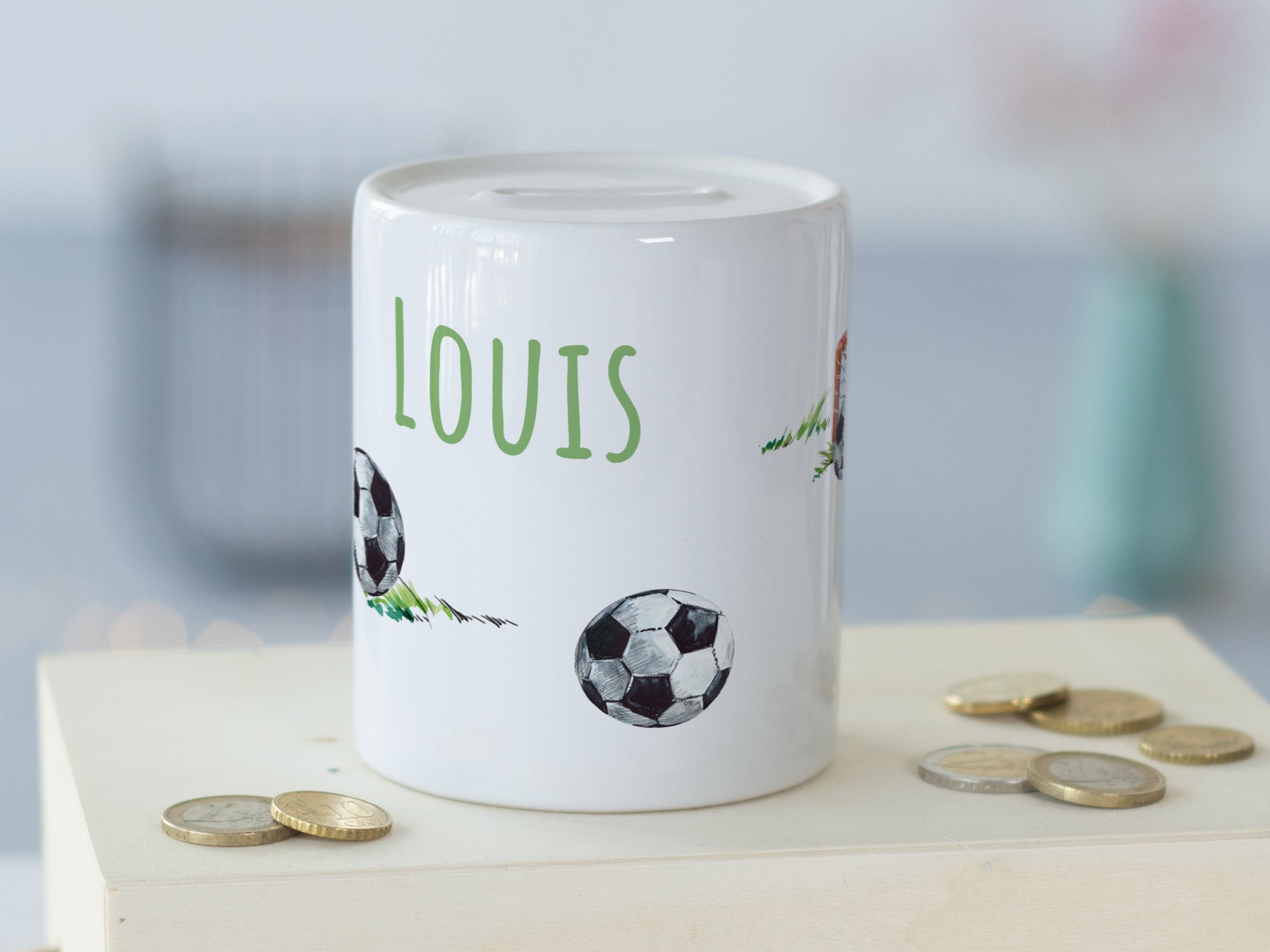 Weißes Sparschwein mit Fußballmotiven und dem Namen Louis.