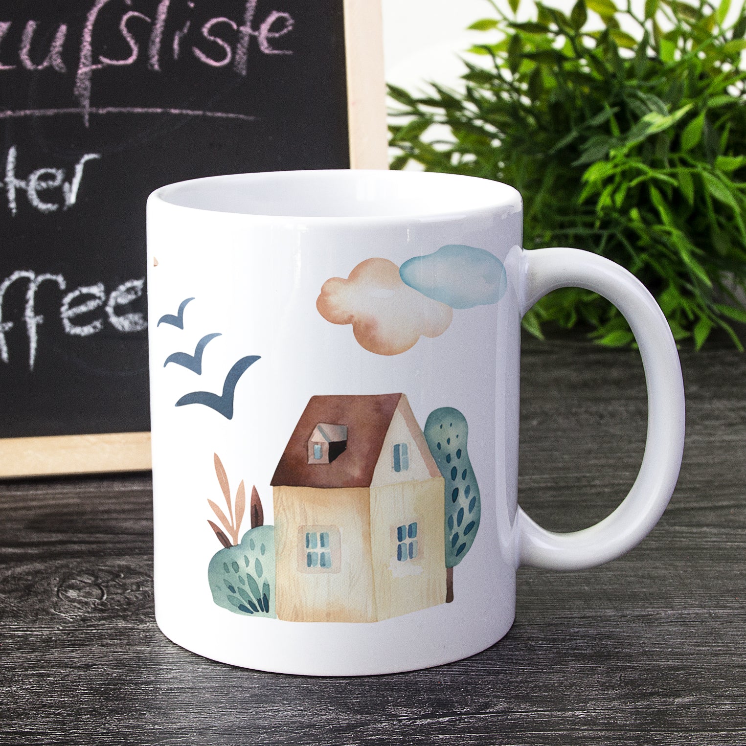Kaffeetasse mit Haus, Wolken und Vögeln in Pastellfarben.