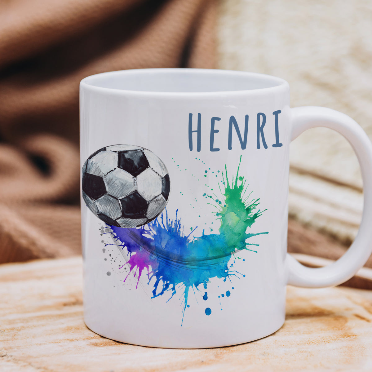 Weißer Becher mit Fußball und buntem Spritzdesign.