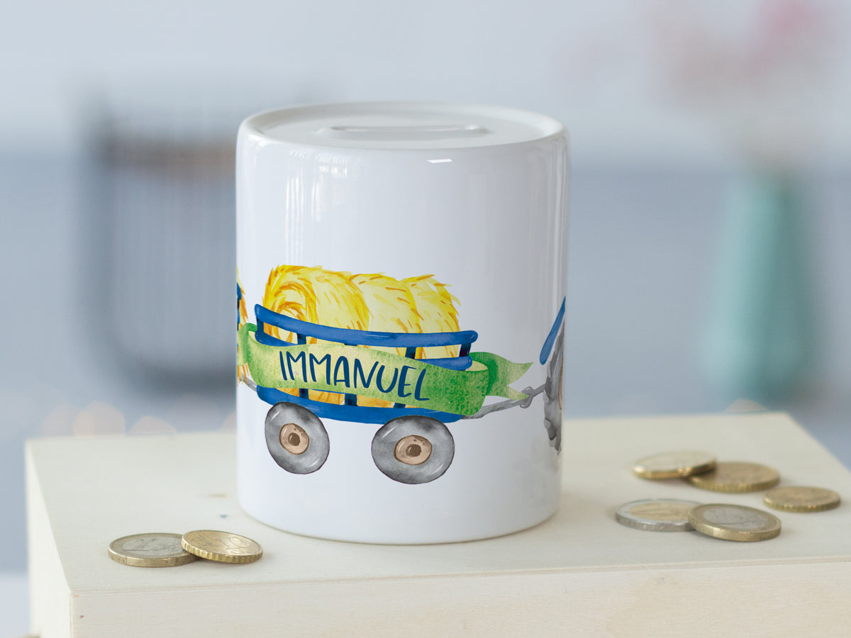 Weißes Sparschwein mit buntem Wagen und "IMMANUEL"-Schriftzug.