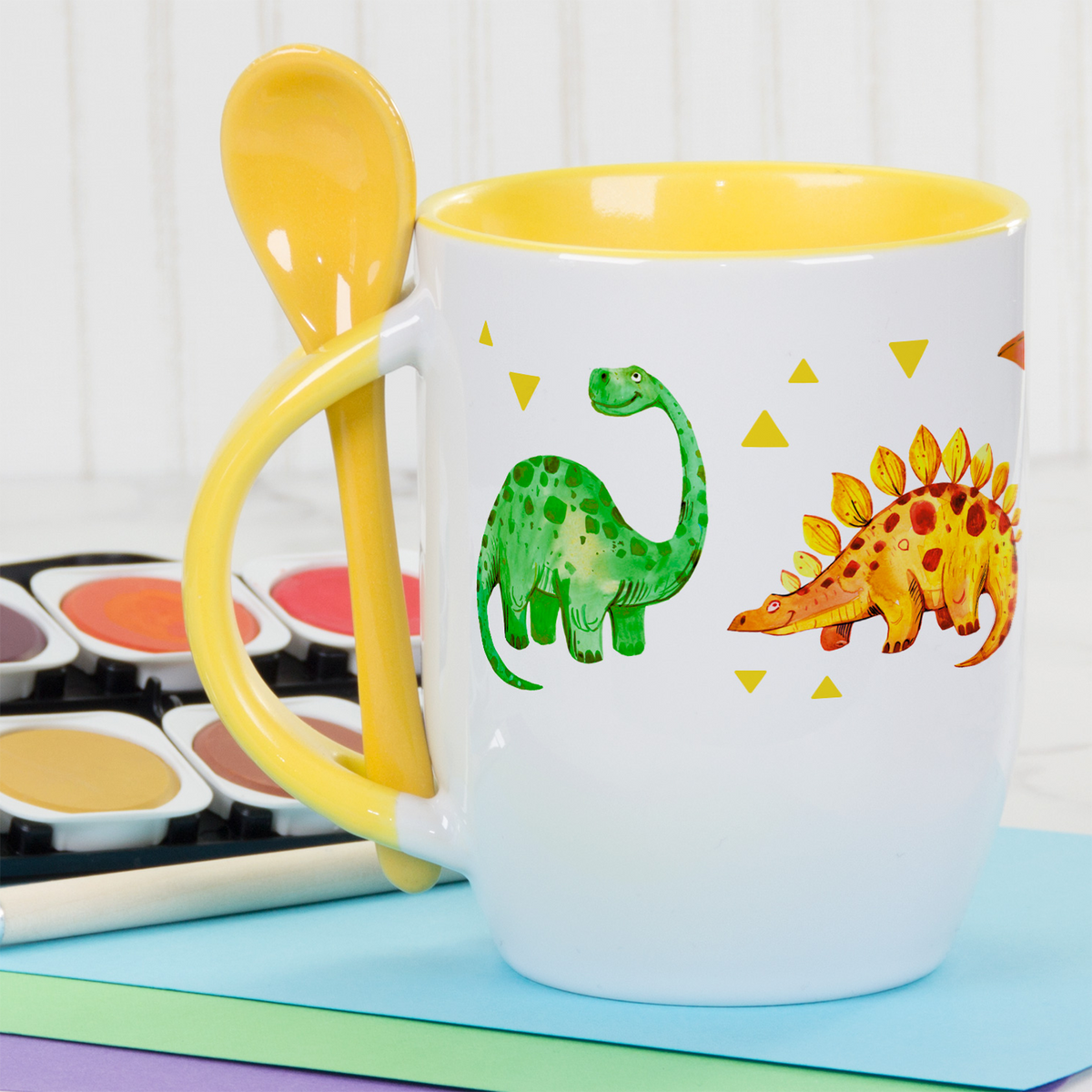 Tasse mit gelbem Innenraum und Dinosaurier-Motiven.