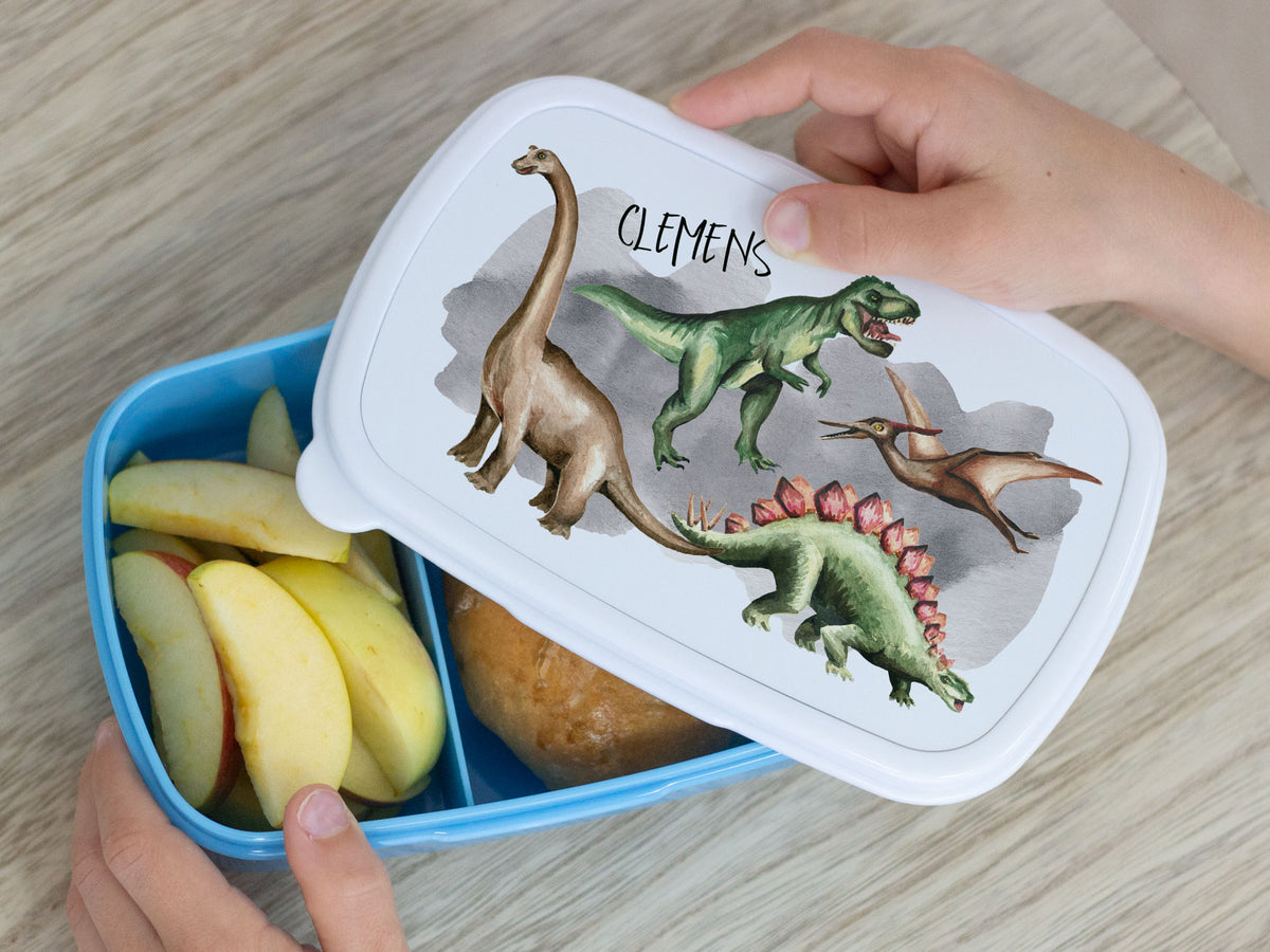 Blaue Brotdose mit Dinosaurier-Motiv und Äpfeln.
