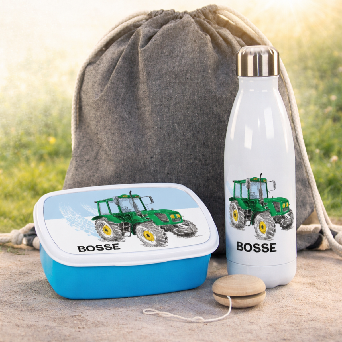 Grüne Brotdose und weiße Trinkflasche mit Traktor-Design.