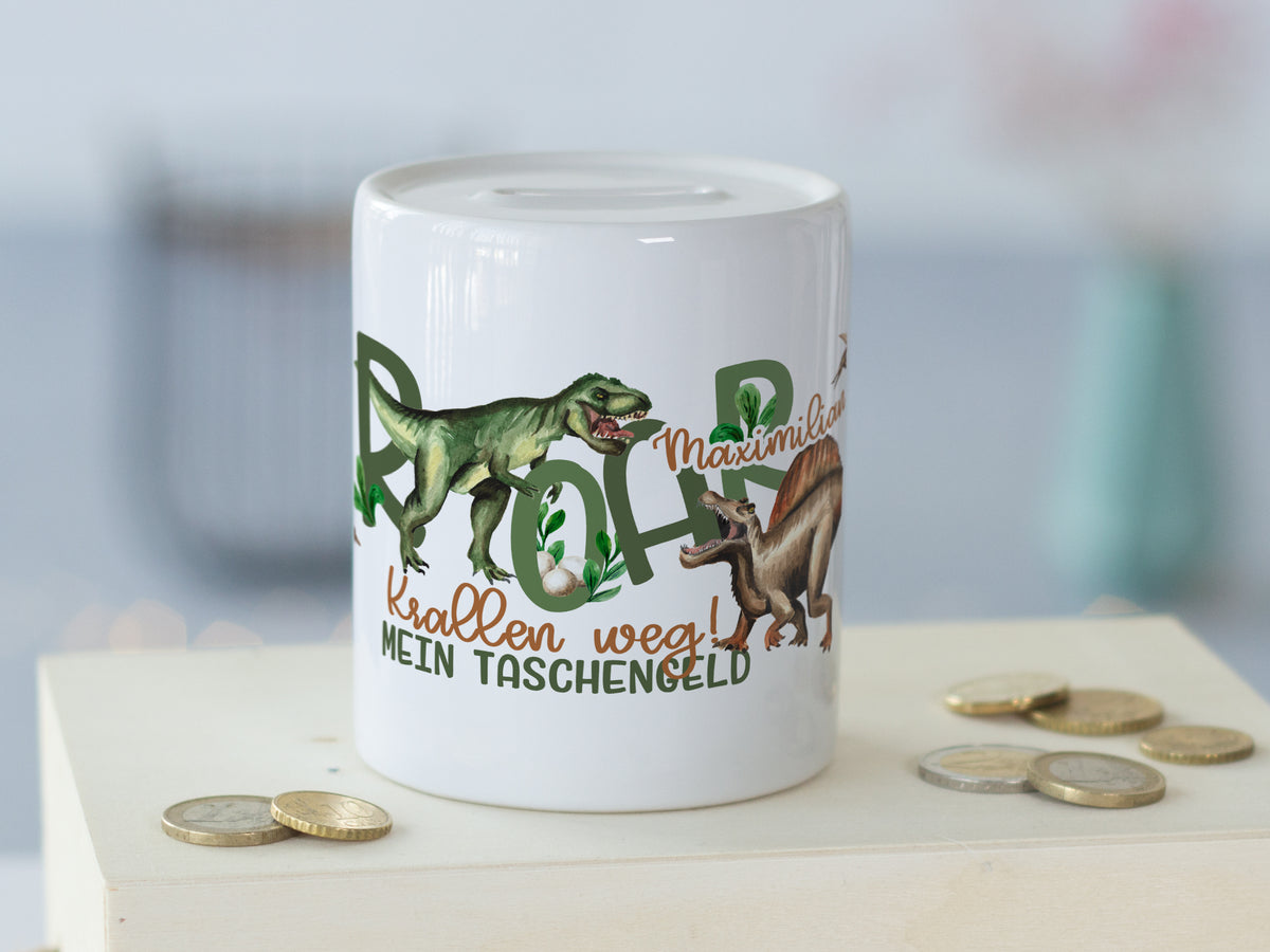 Weißes Sparschwein mit Dinosauriern und buntem Schriftzug.
