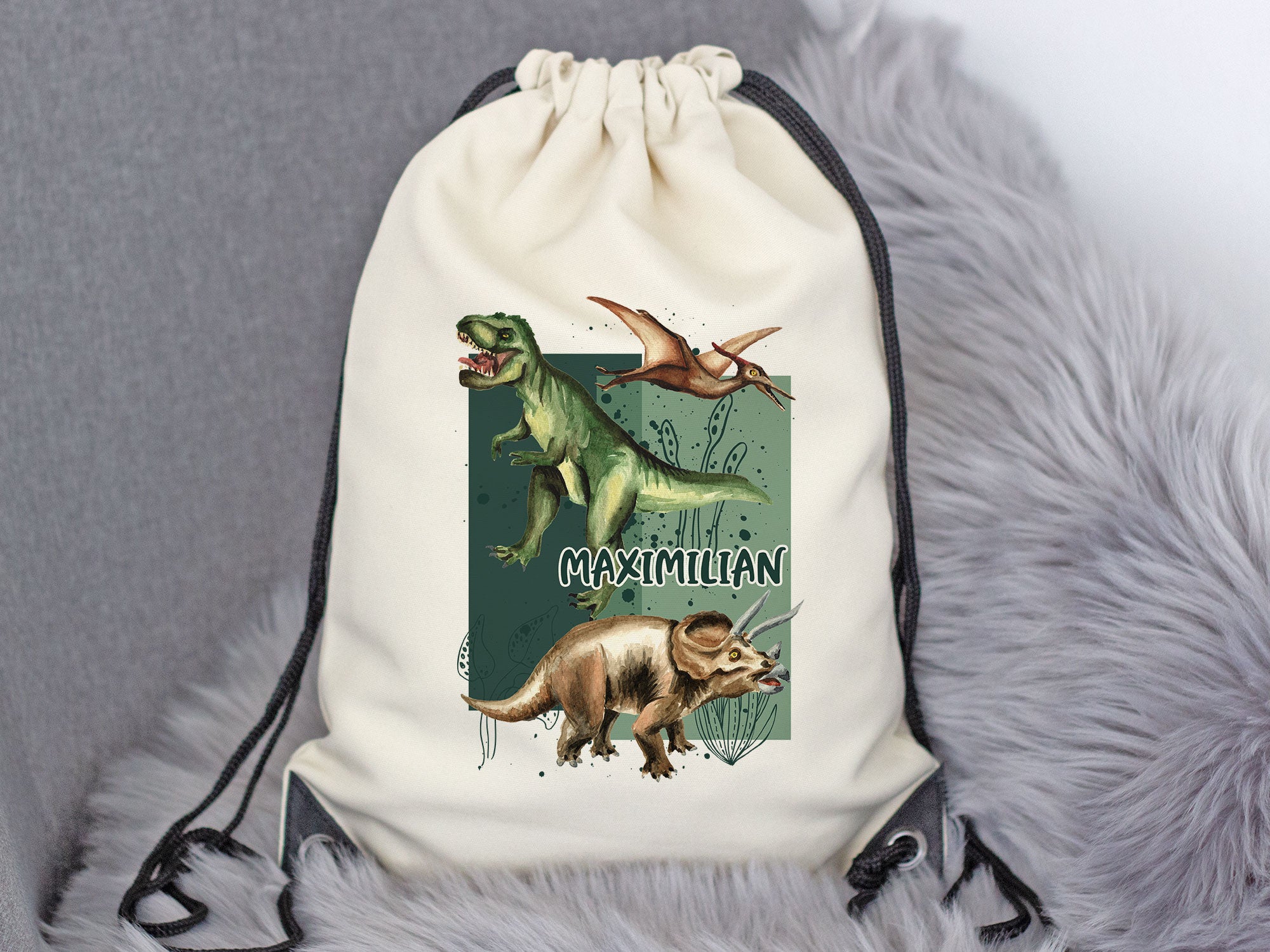 Beige Rucksack mit Dinosaurier-Motiven und Namen Maximilian.