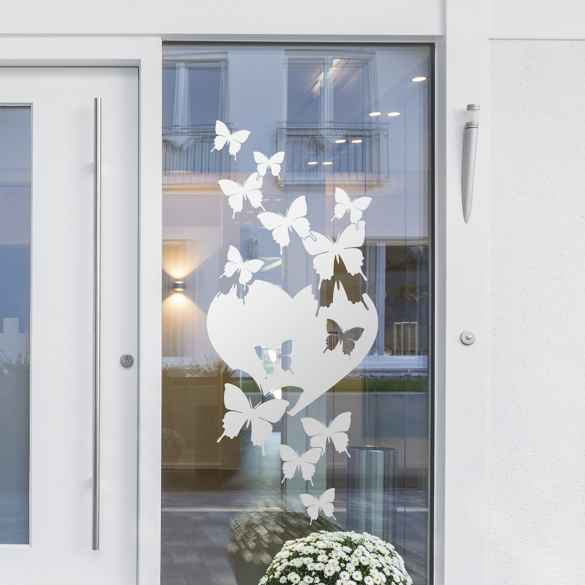 Weißes Fensterdekor mit Schmetterlingen und Herzmotiv.