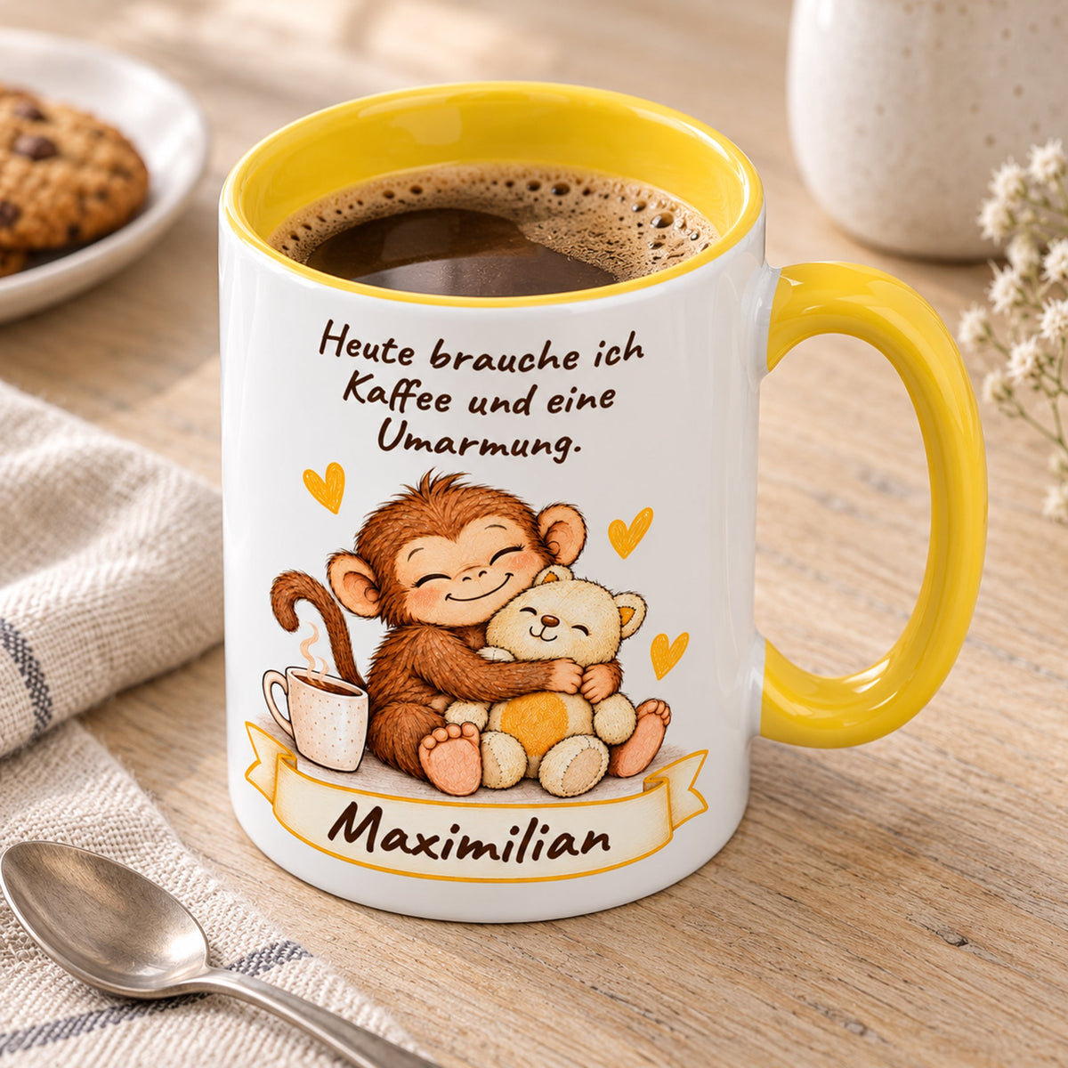 Schrägansicht: gelbe personalisierte Tasse mit Baby-Affe, Motiv Umarmung mit Teddy, Beispielname Maximilian