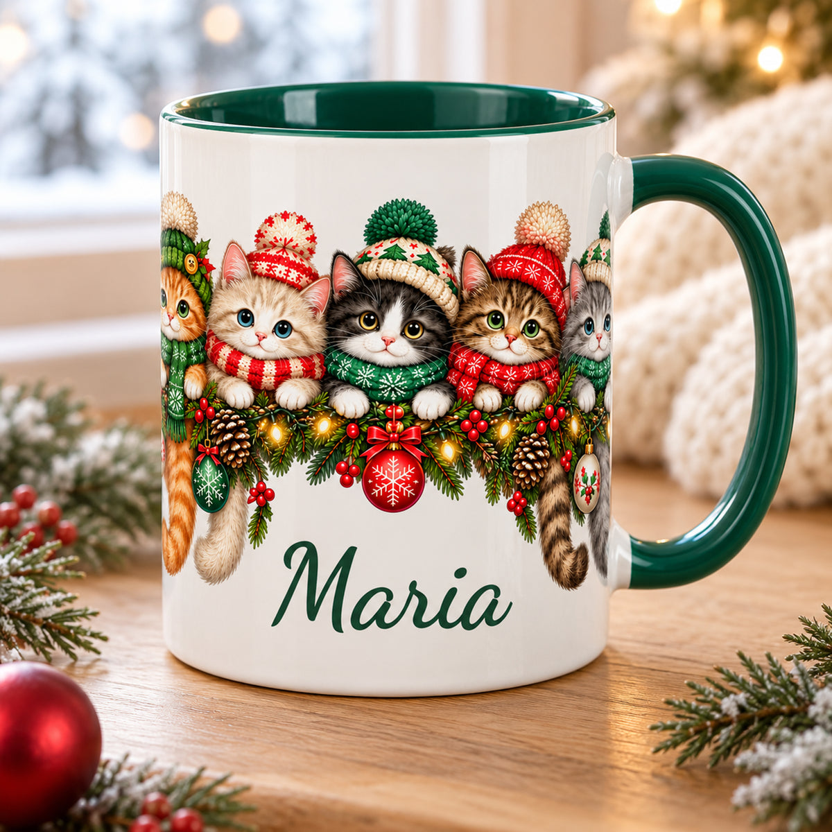 Weiße Weihnachtstasse mit grünem Henkel, grünem Inneren, Katzen in Wintermützen und einem Wunschnamen auf einem Holztisch.
