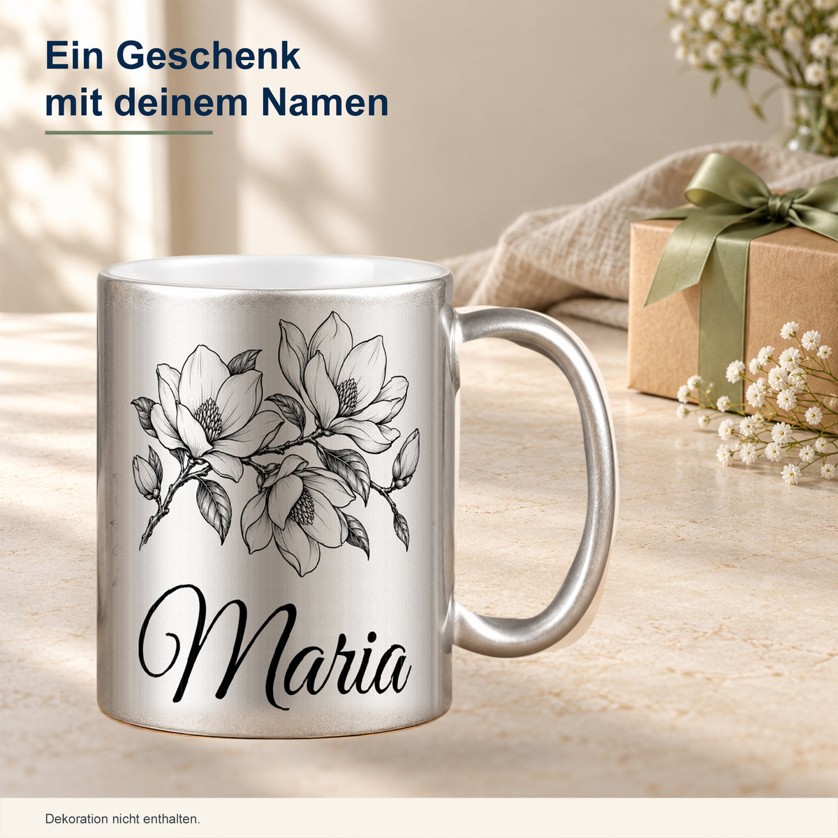 Silberne Tasse mit schwarzem Magnolienmotiv und Wunschnamen als persönliche Geschenkidee in dekorierter Umgebung.