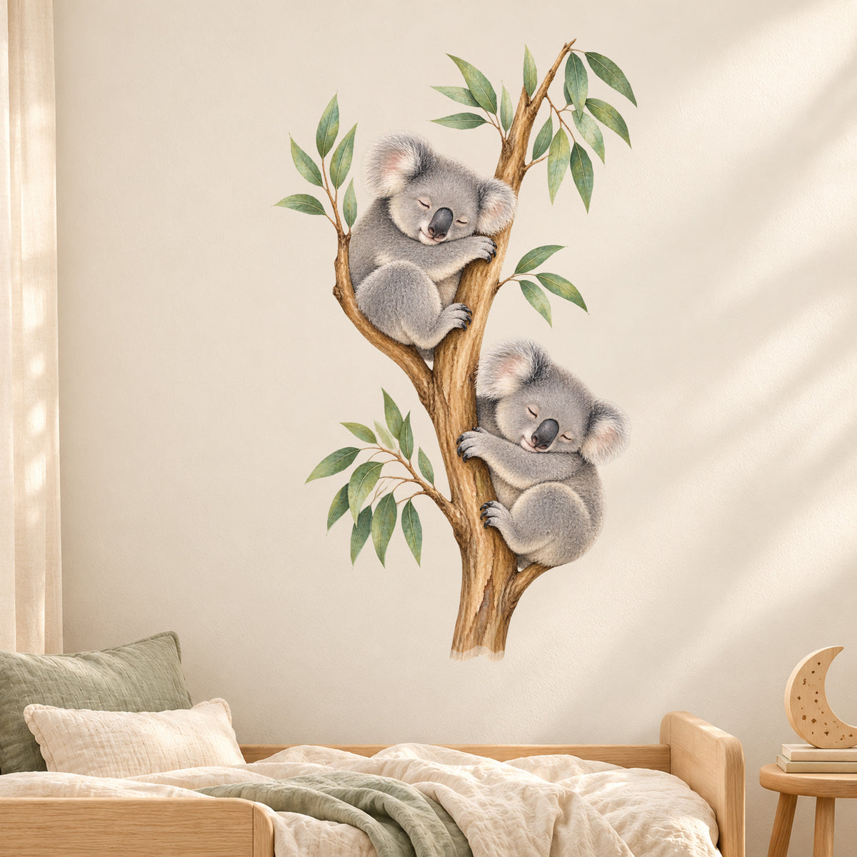 Koala-Wandtattoo Schlafenszeit an einer hellen Kinderzimmerwand über einem Bett mit grünen Kissen und einer kleinen Monddekoration.