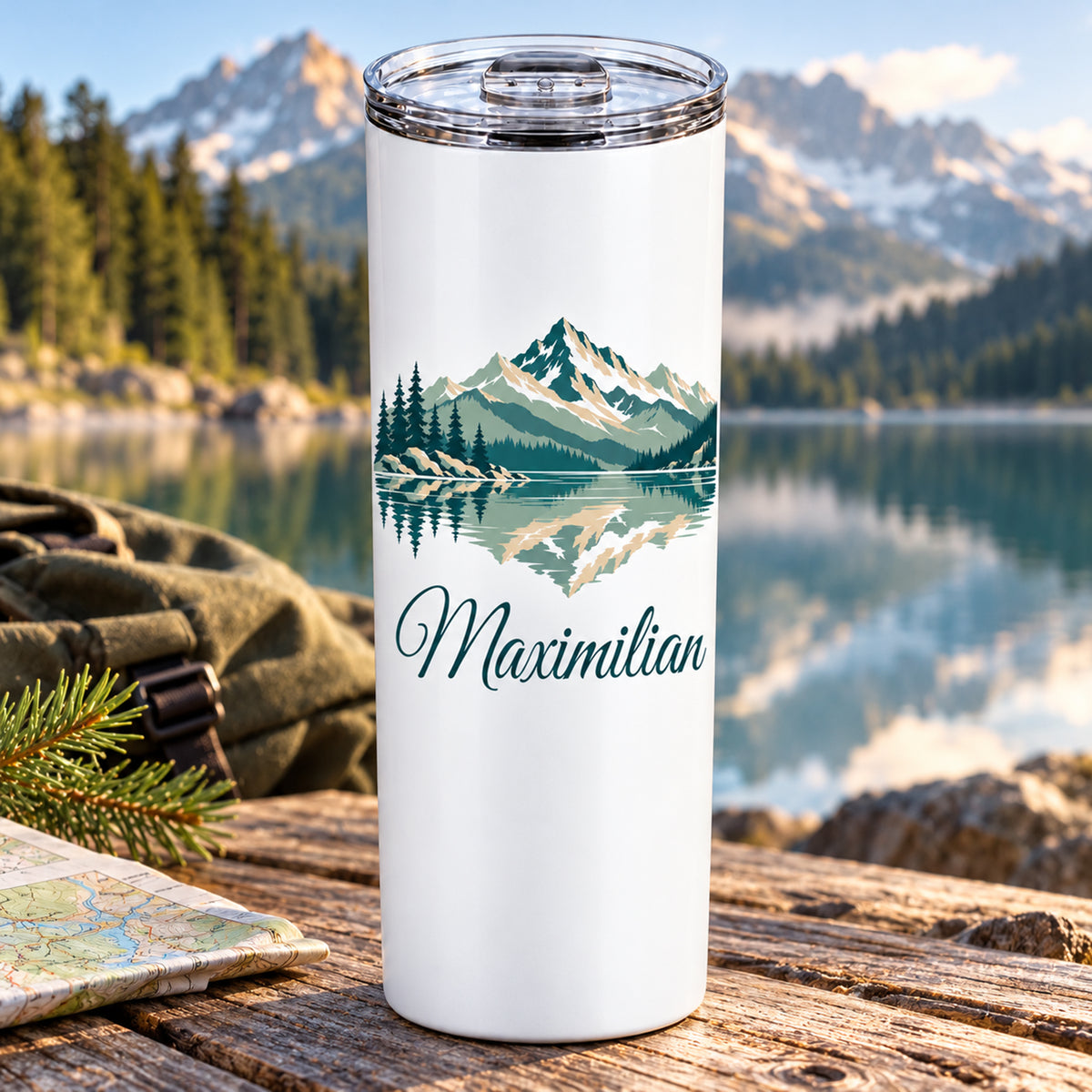 Thermobecher mit Bergsee und Tannen und Wunschname vor einem stillen Bergsee.