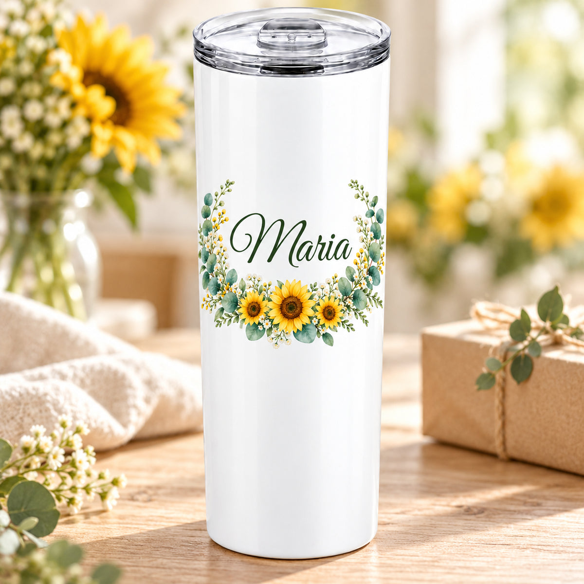 Weißer Thermobecher mit Motiv Sonnenblüten, Blumenranke und Name Wunschname auf einem dekorierten Geschenktisch.