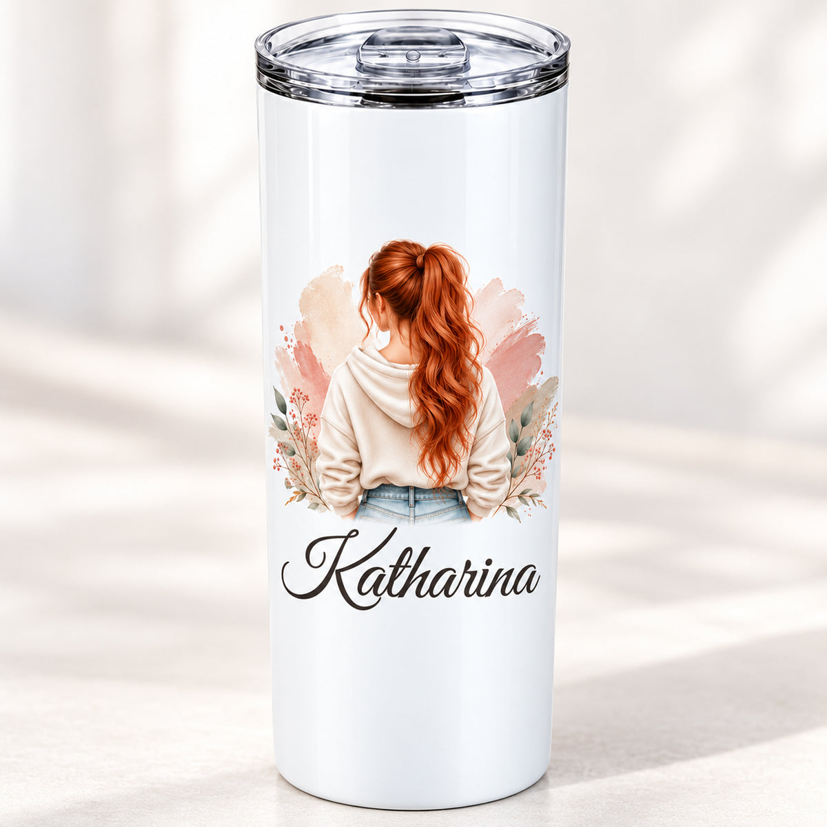 Nahansicht des Frauenmotivs mit kupferrotem Pferdeschwanz und cremefarbenem Hoodie und personalisiertem Namen auf dem weißen Thermobecher.
