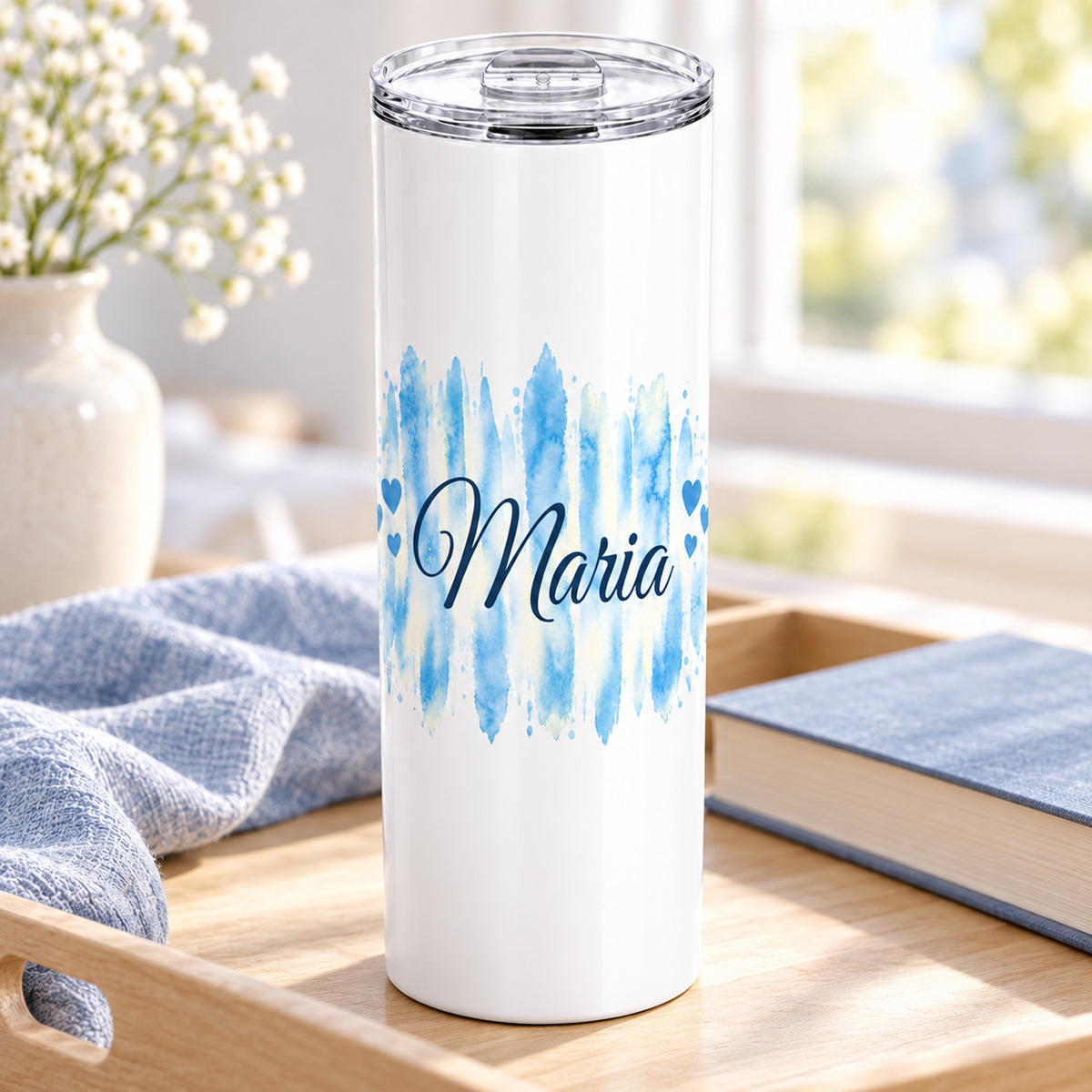 Weißer Thermobecher mit Motiv Himmelherz, personalisiertem Namen in einer wohnlichen Umgebung.