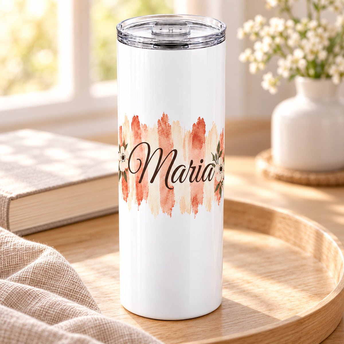 Weißer Thermobecher mit Motiv Terrakottablüte, personalisiertem Namen in einer wohnlichen Umgebung.