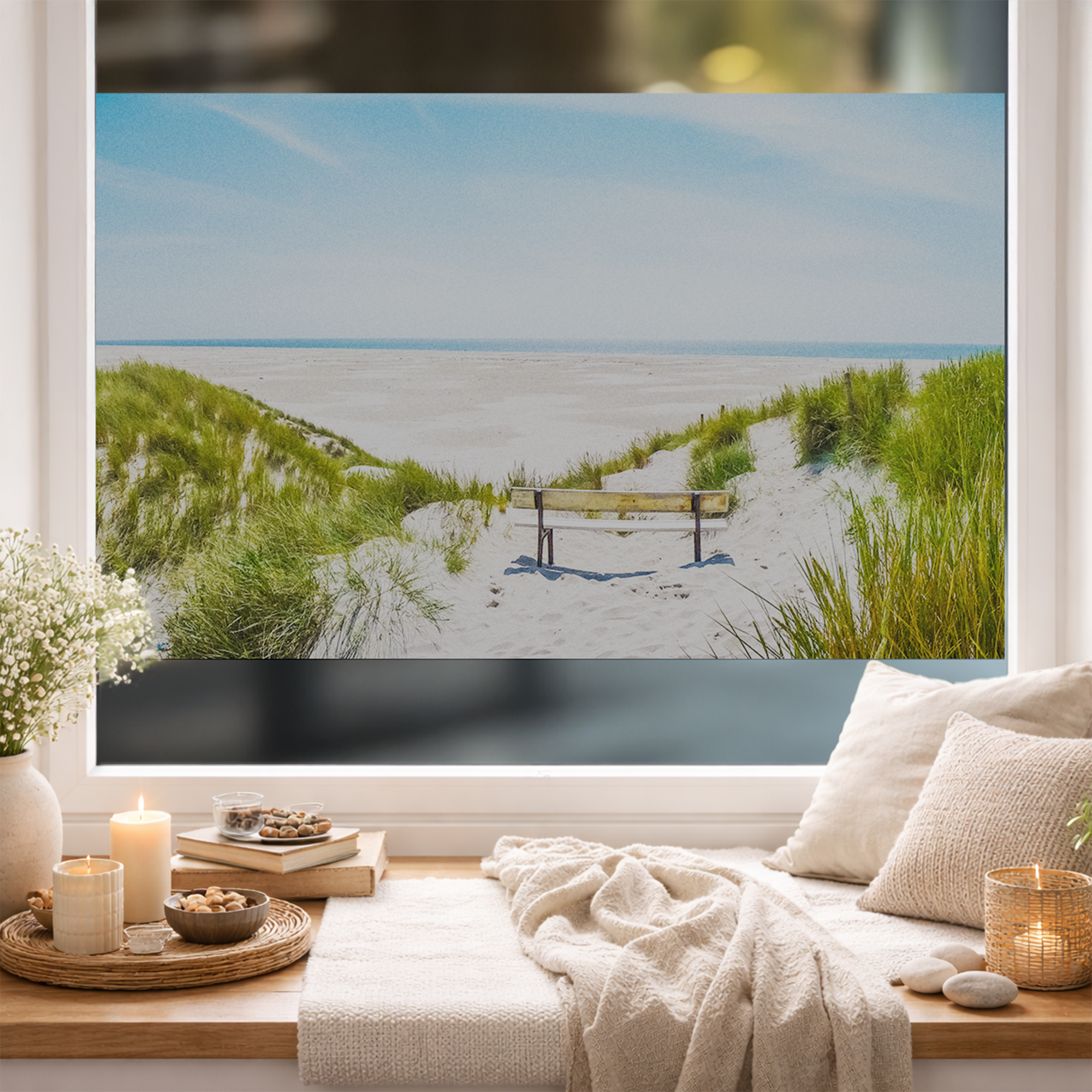 Blick auf einen Strand mit Bank, grüne Gräser, blauer Himmel.