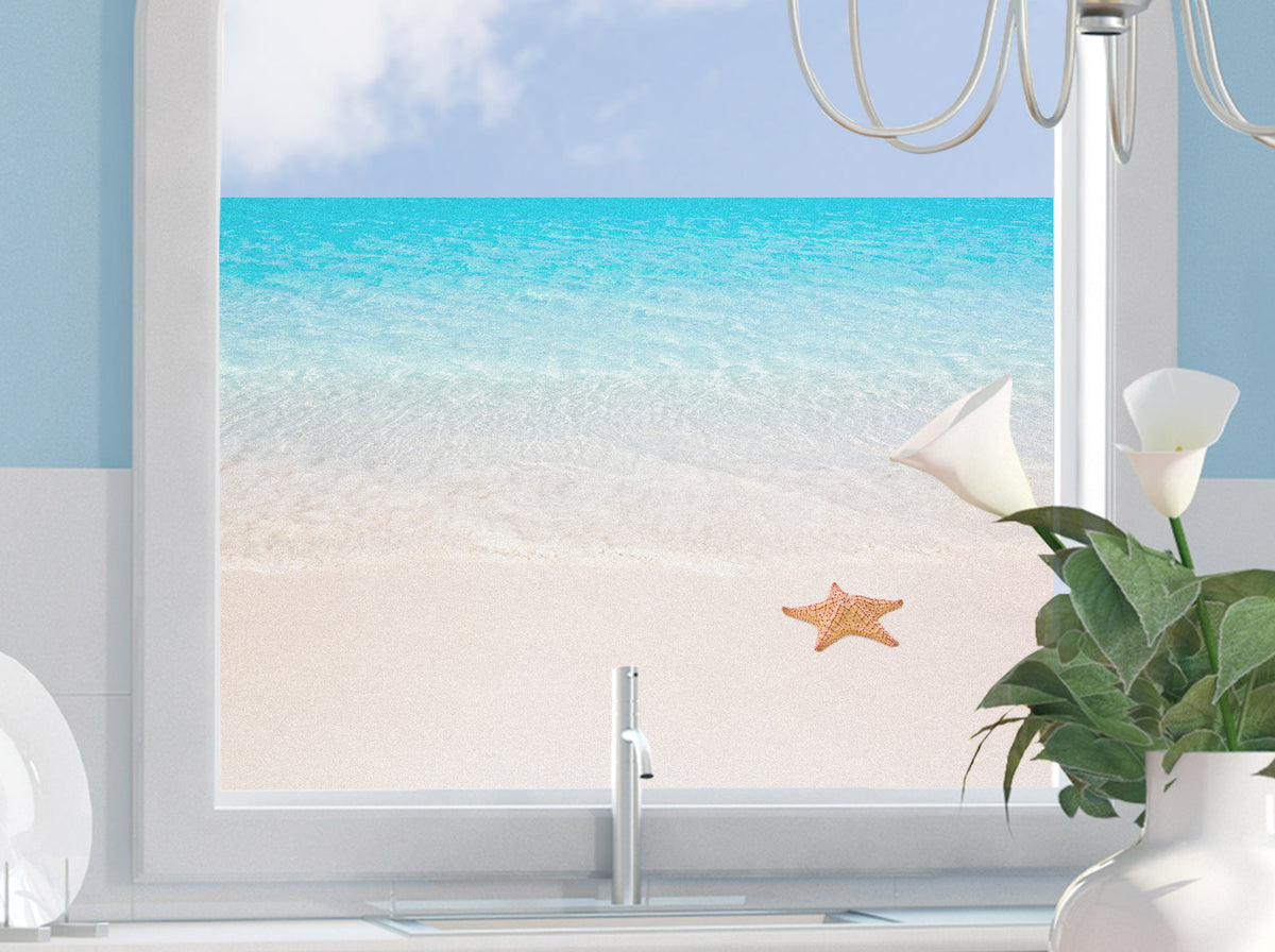 Blick aus dem Fenster auf türkisfarbenes Wasser und Sandstrand.