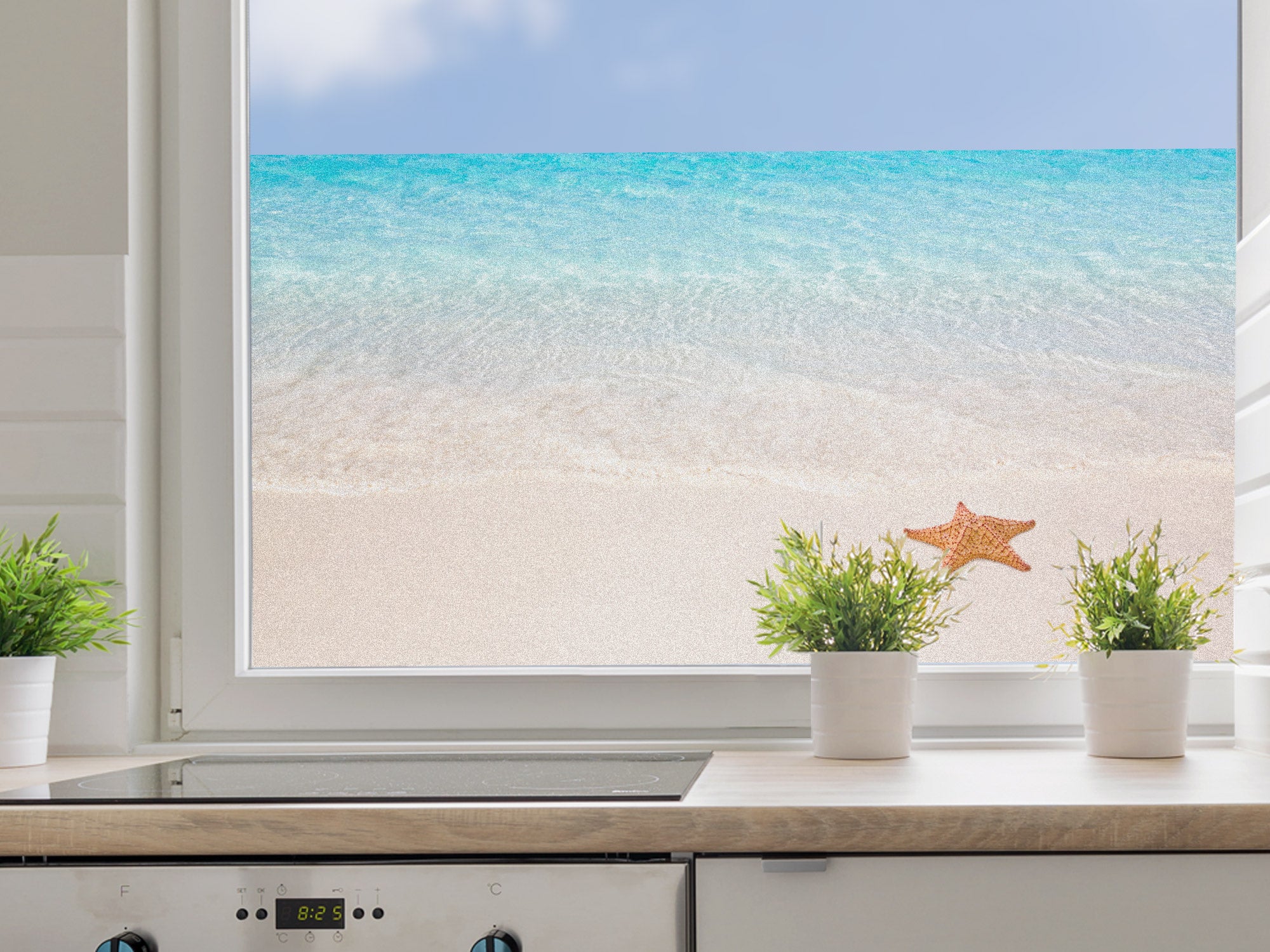 Küchenfenster mit Meerblick, türkisfarbenes Wasser, grüne Pflanzen.