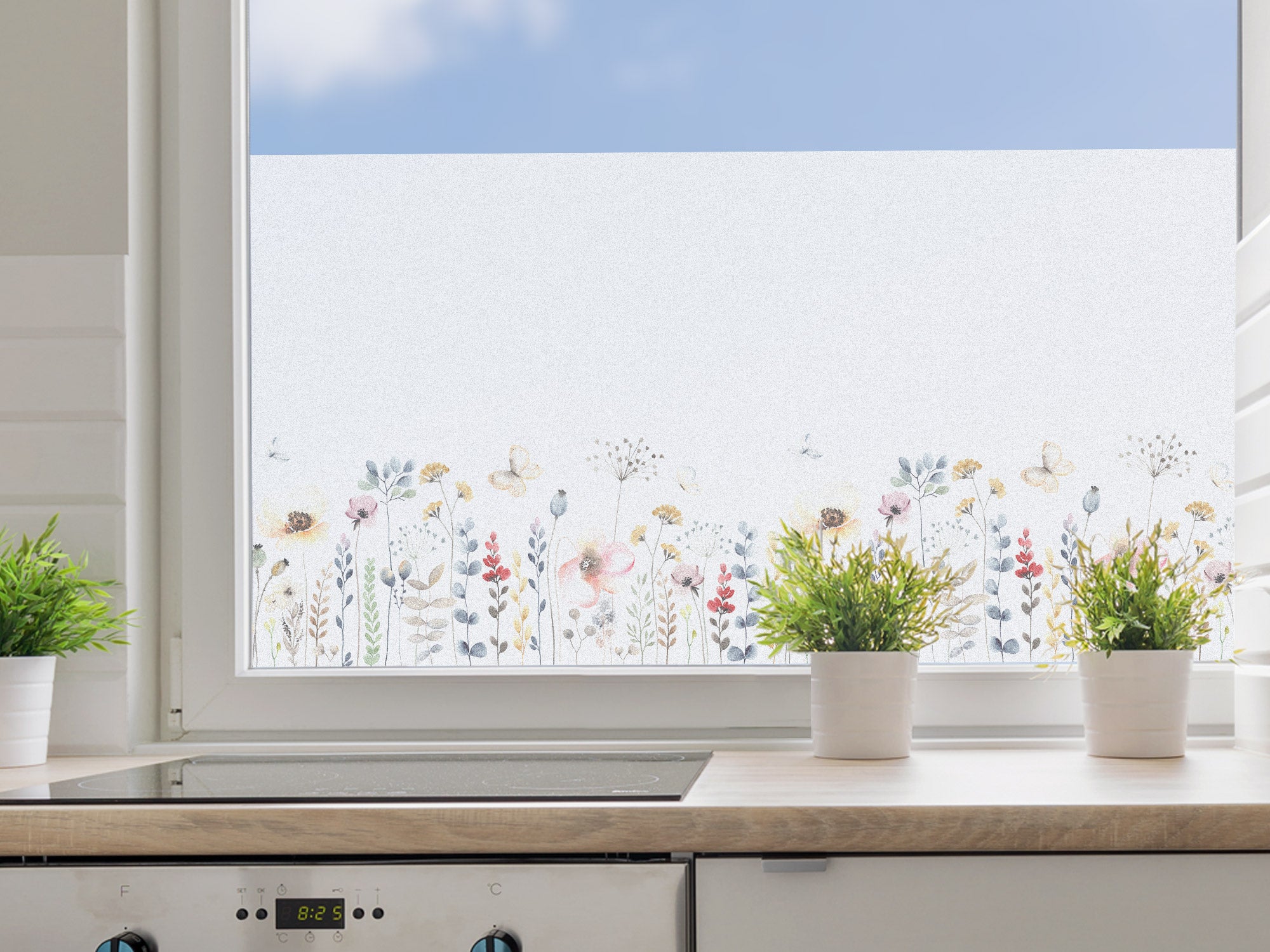 Fenster mit floralen Mustern, helle Farben, Pflanzen im Vordergrund.
