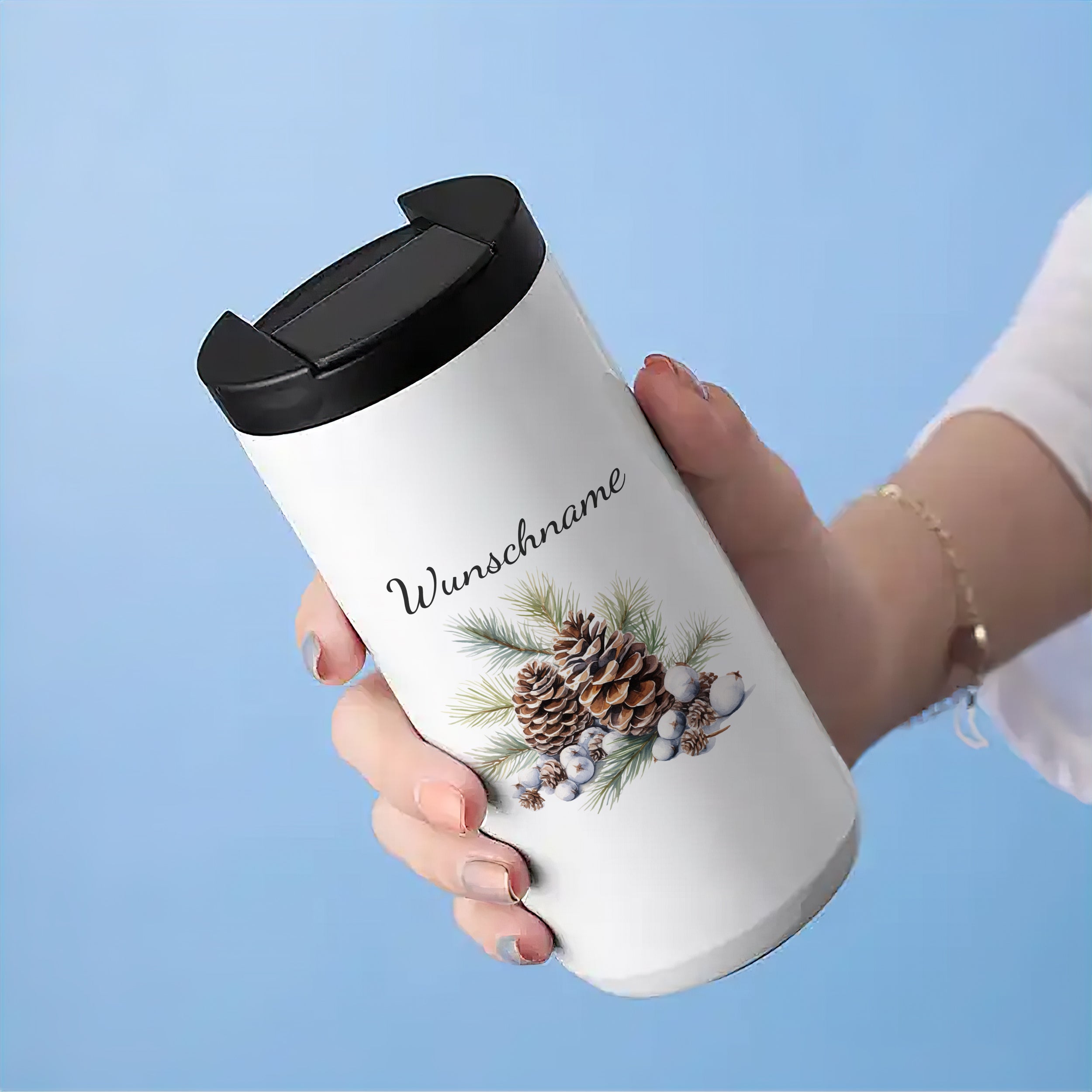 Weißer Thermobecher mit winterlichem Tannenzapfen-Motiv.