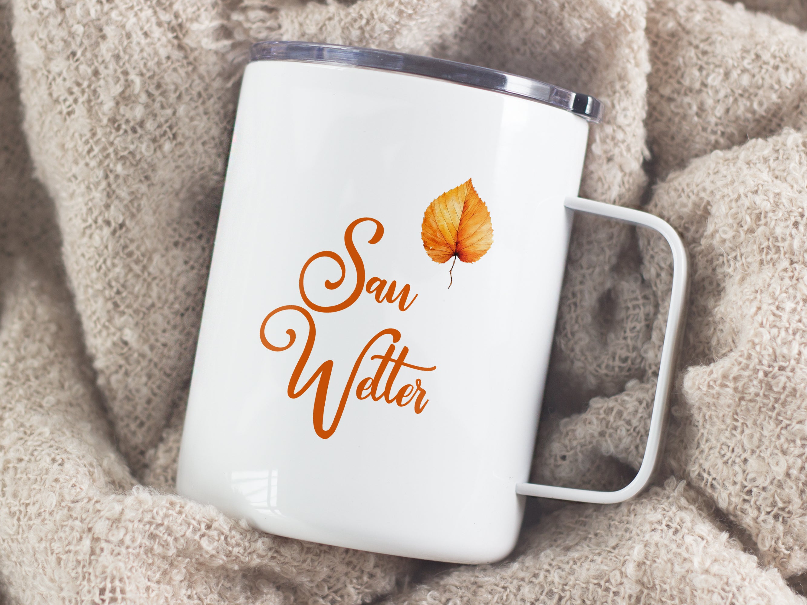 Weißer Becher mit orangefarbenem Schriftzug "Sau Wetter" und Blatt.