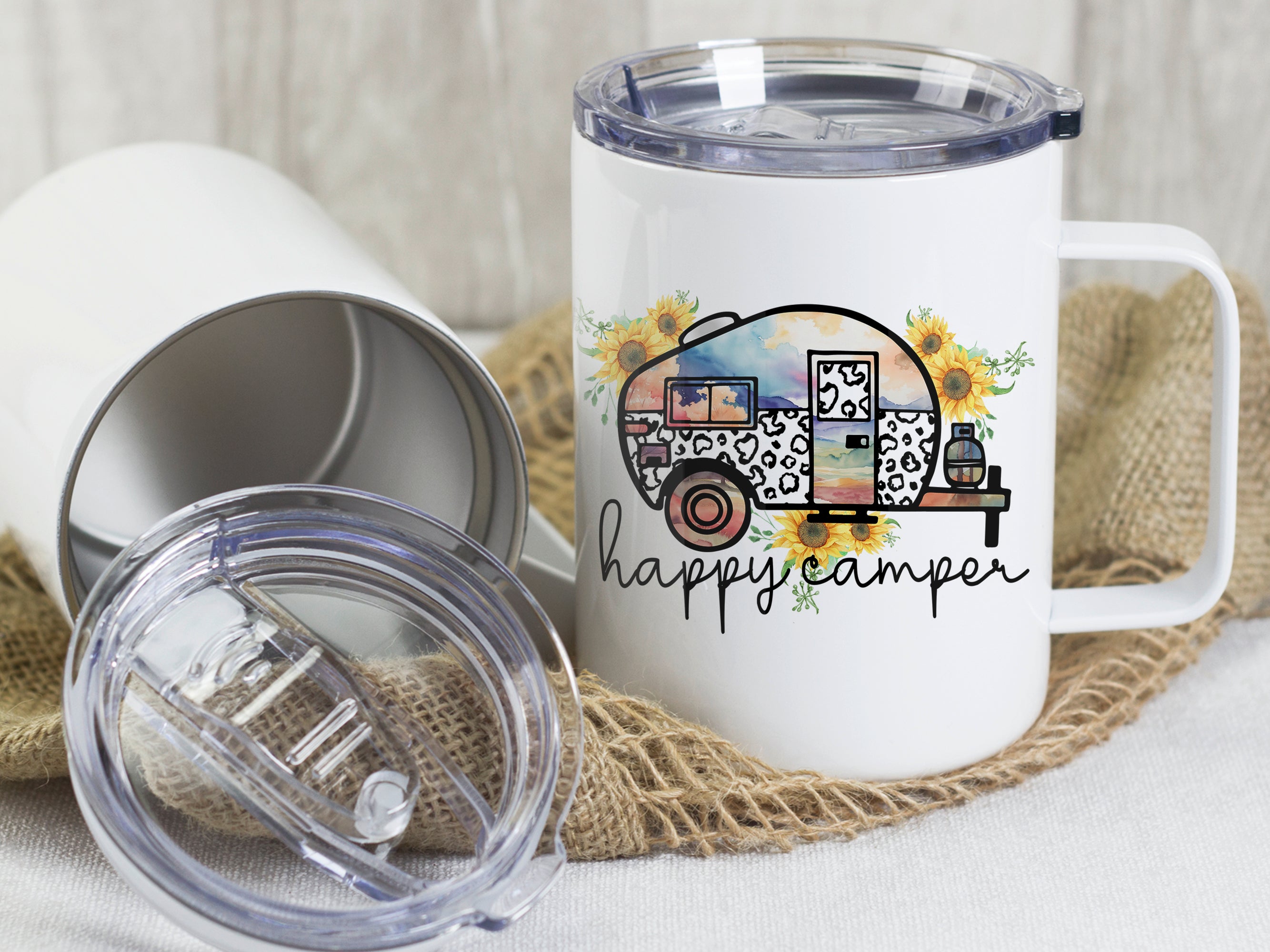 Becher mit buntem Wohnwagen-Motiv und "happy camper"-Schriftzug.