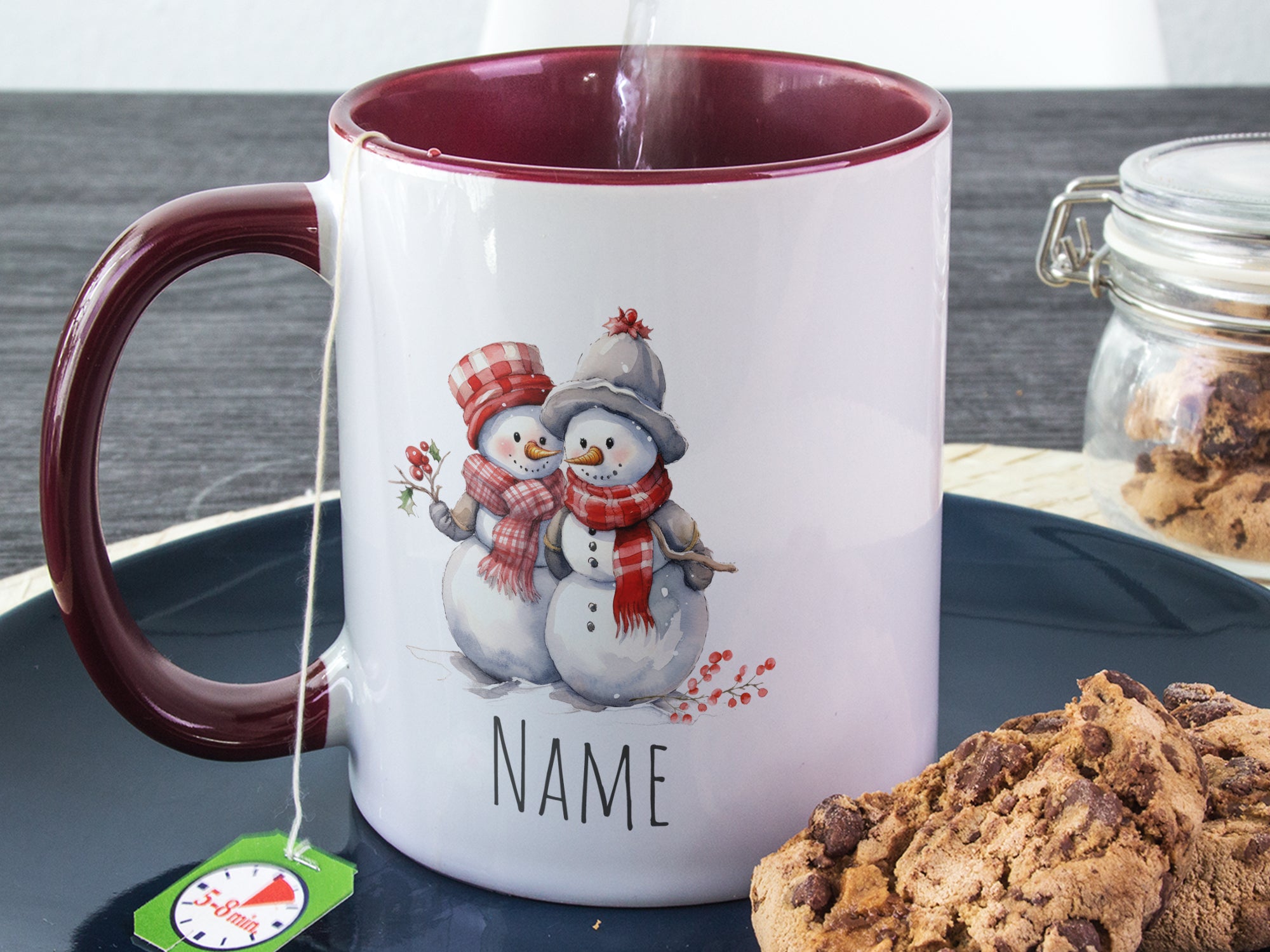 Kaffeetasse mit Schneemann-Motiv und bordeauxrotem Henkel.