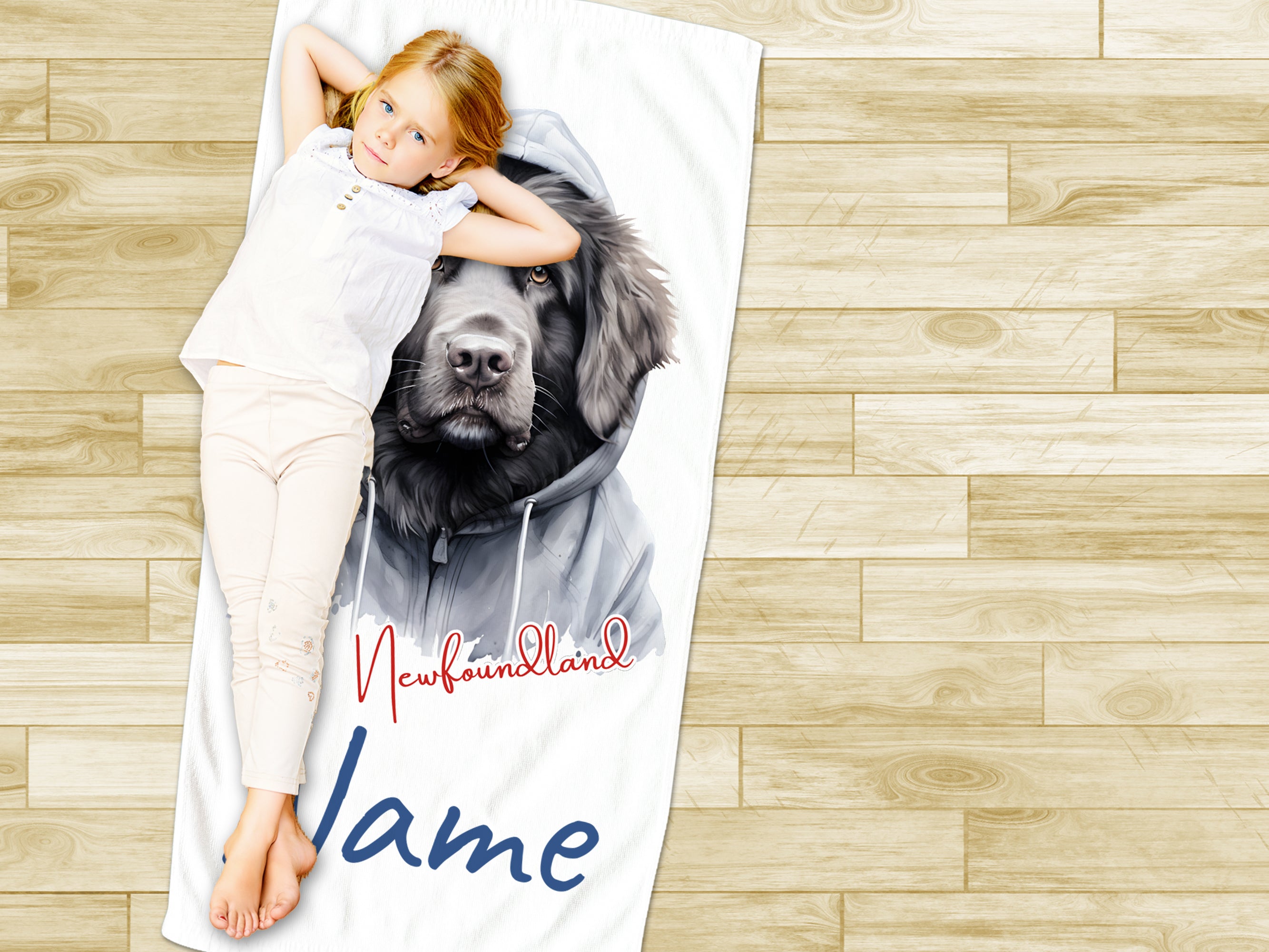 Mädchen liegt auf Handtuch mit Newfoundland-Hund und Namen.