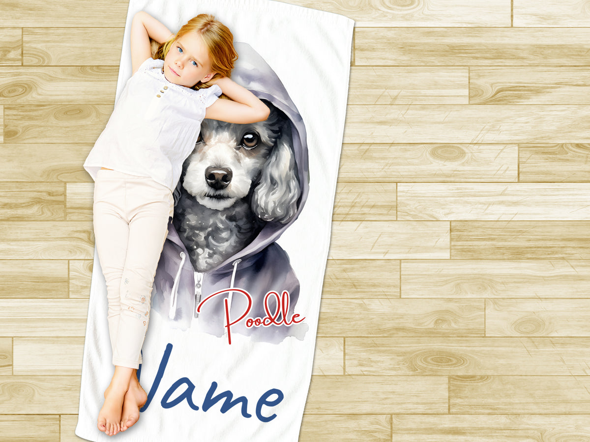 Mädchen liegt auf Handtuch mit Pudel-Motiv in Grau.