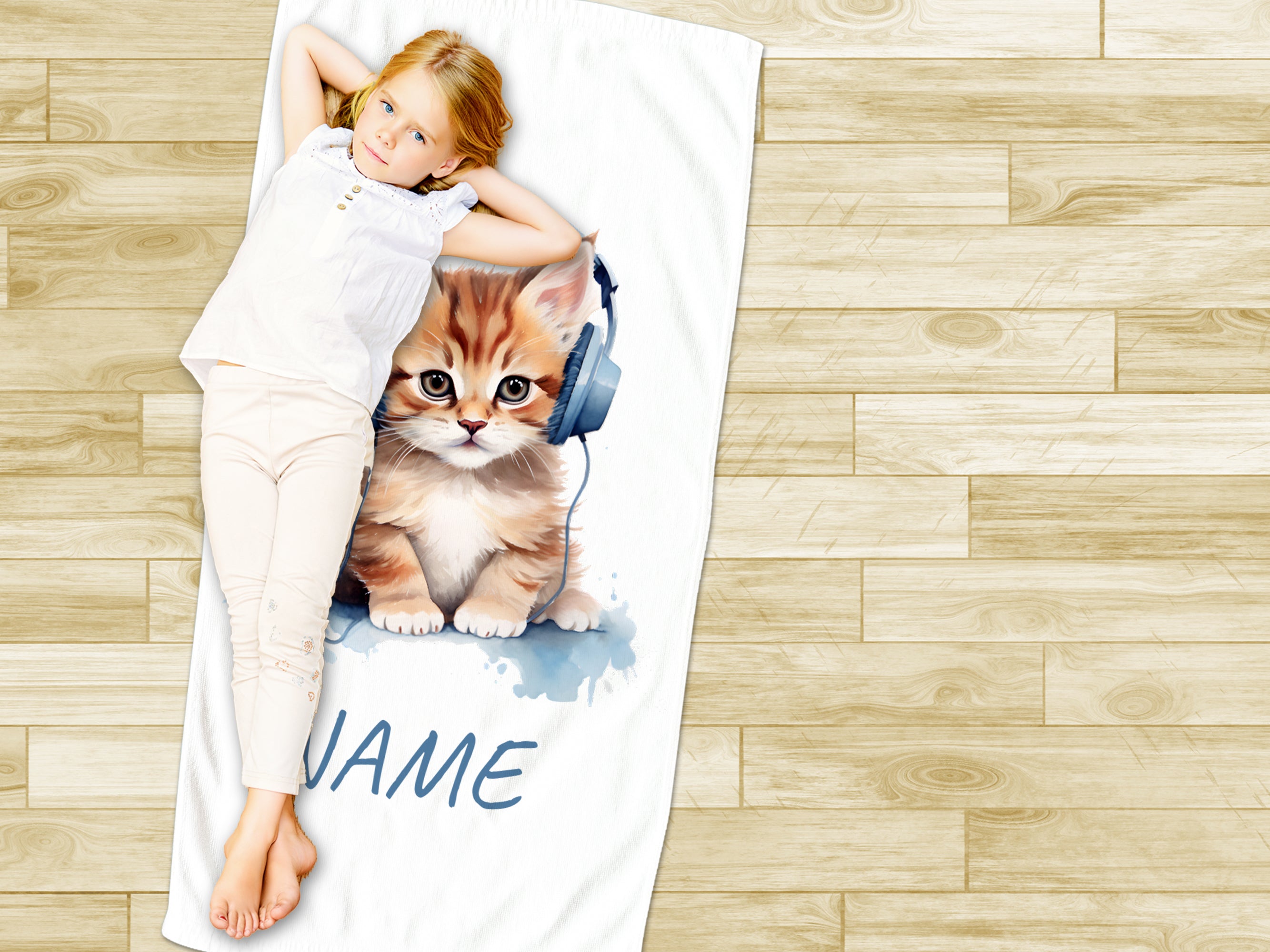 Mädchen liegt auf einem Handtuch mit Katzenmotiv.