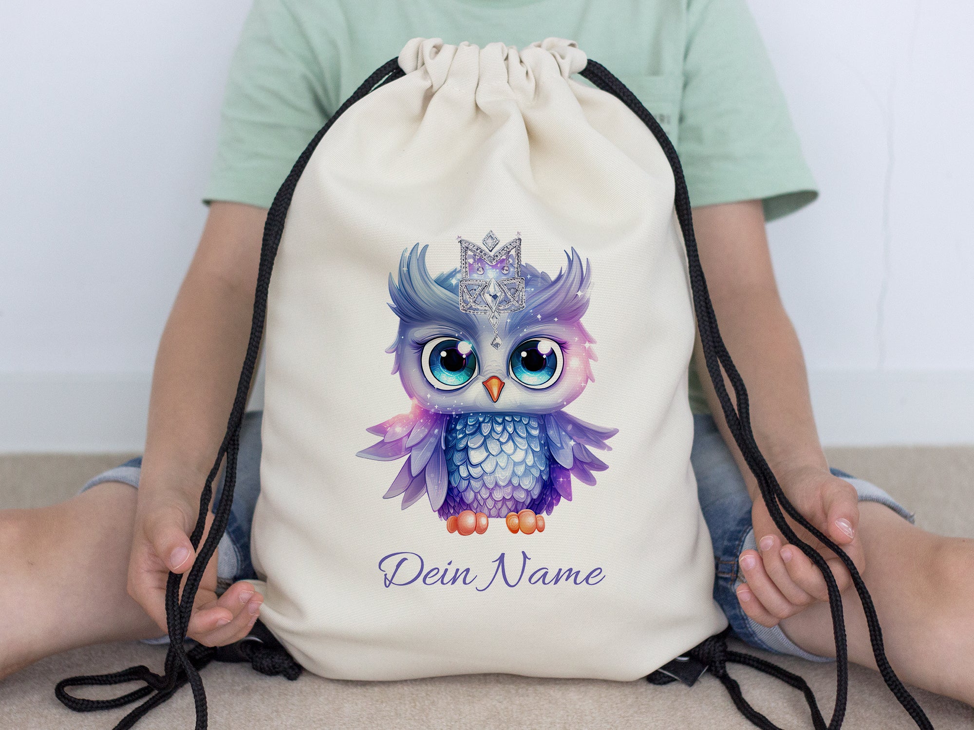 Beiger Turnbeutel mit buntem Eulenmotiv und personalisiertem Namen.