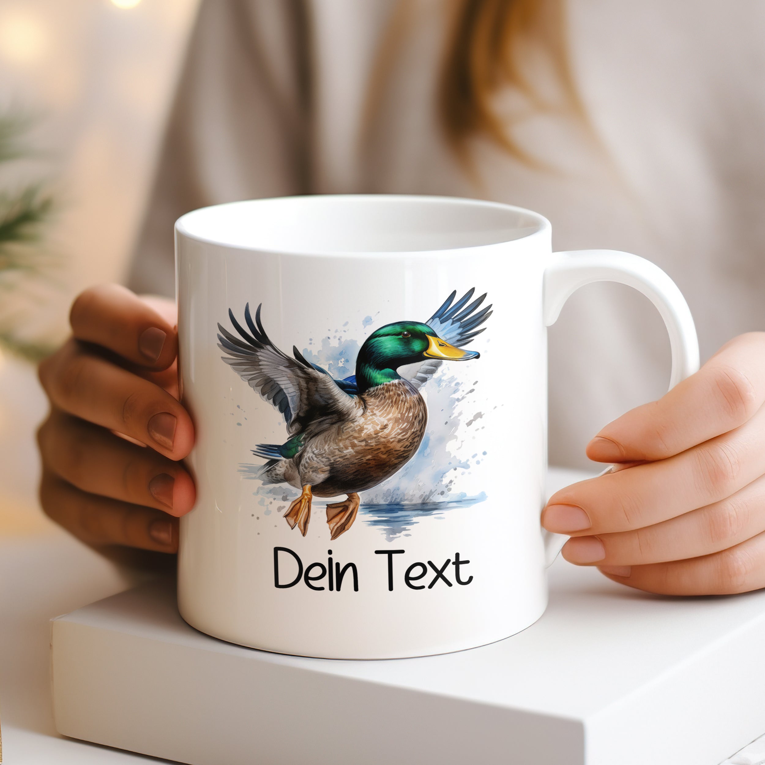 Weißer Kaffeebecher mit fliegender Ente und personalisiertem Text.