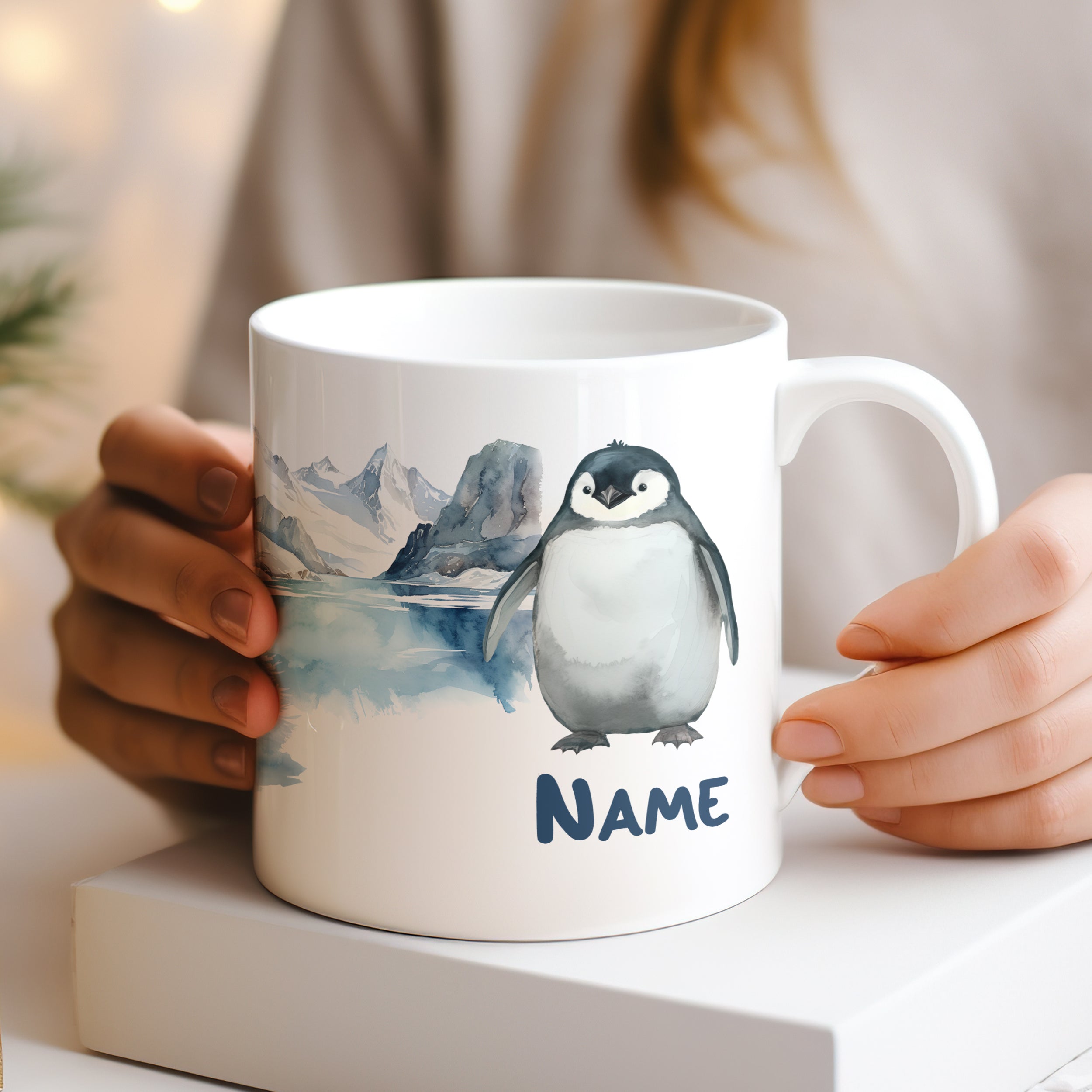 Weißer Becher mit Pinguin-Motiv und personalisiertem Namen.