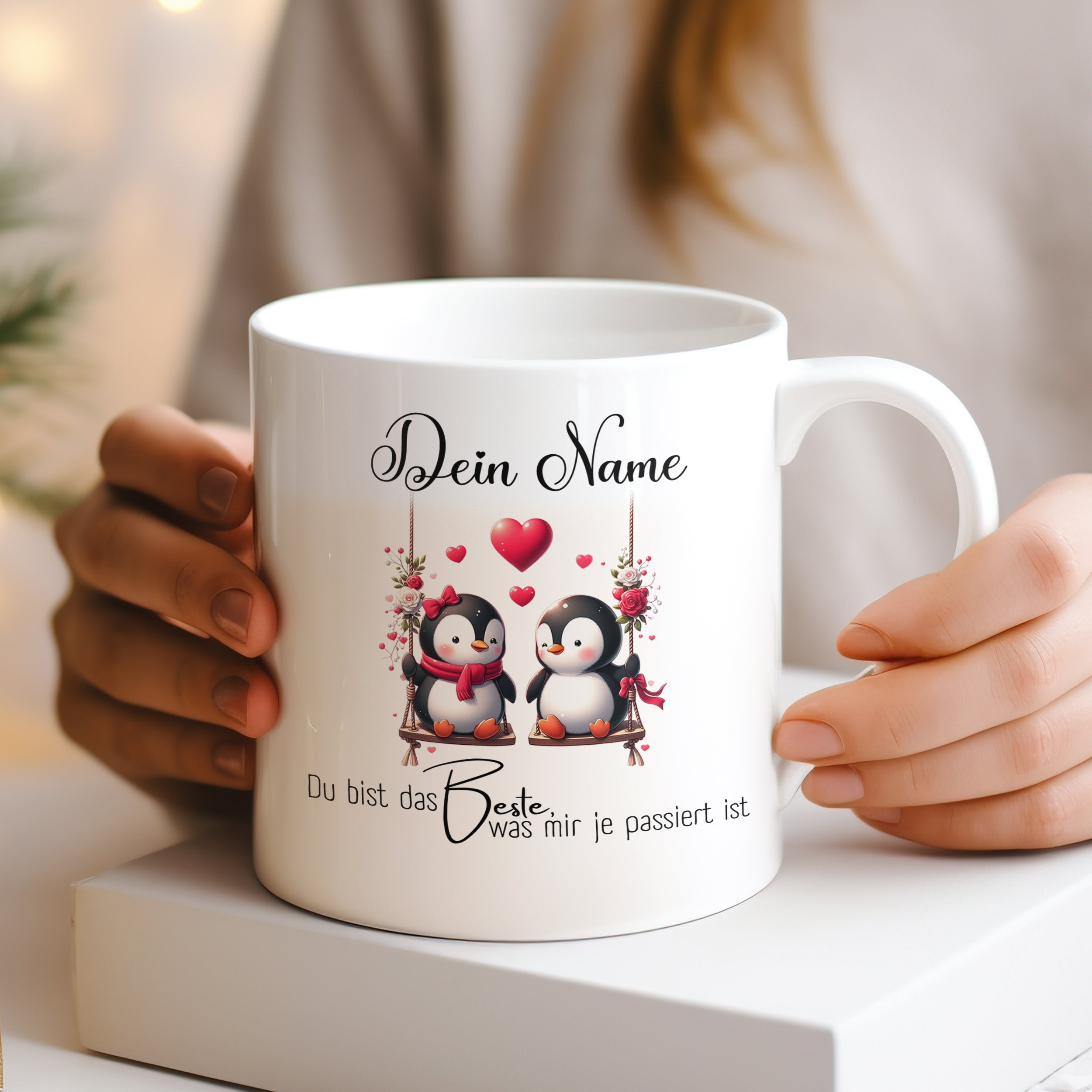 Weißer Becher mit zwei Pinguinen und Herzmotiven.