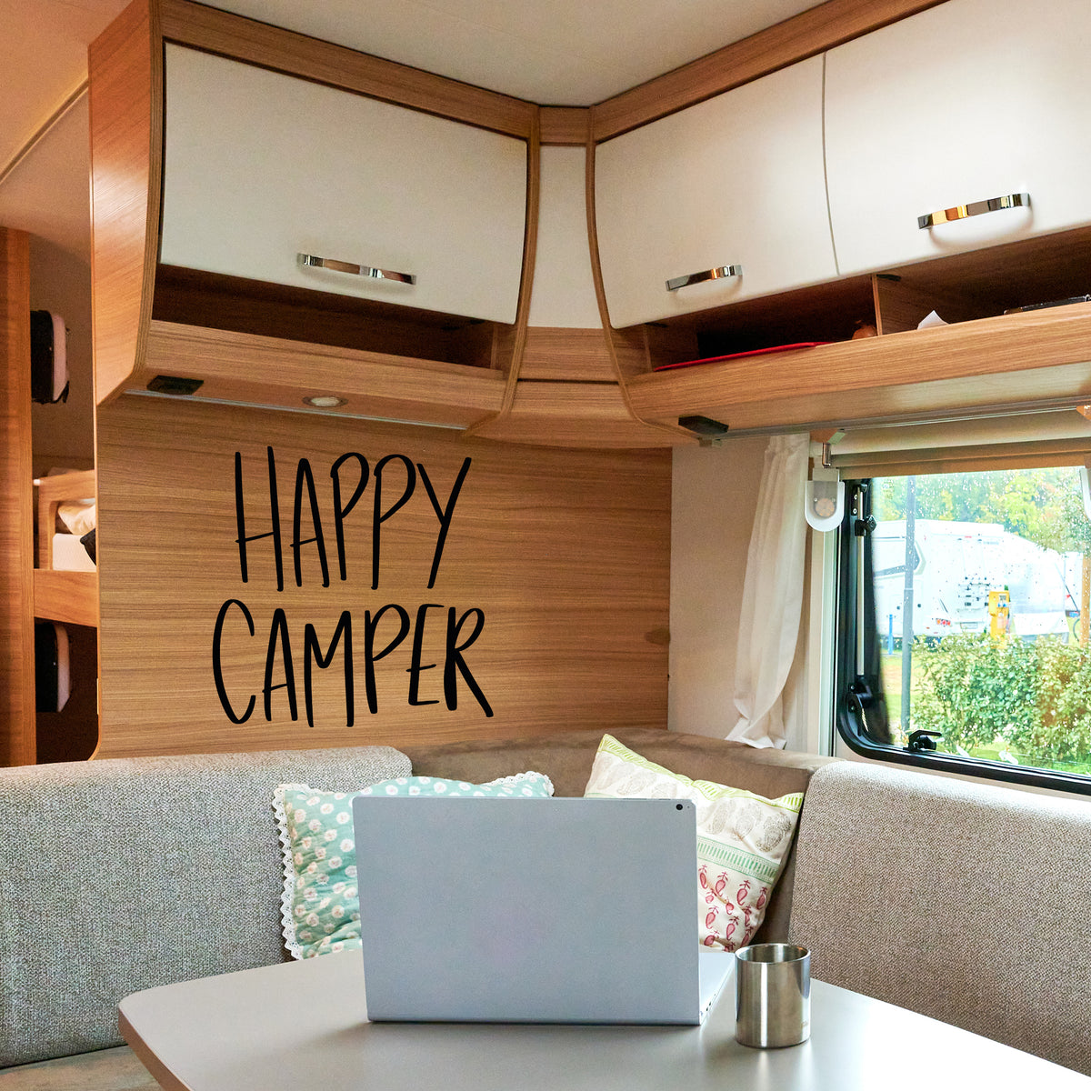 Gemütlicher Wohnmobil-Innenraum mit "HAPPY CAMPER"-Schriftzug.