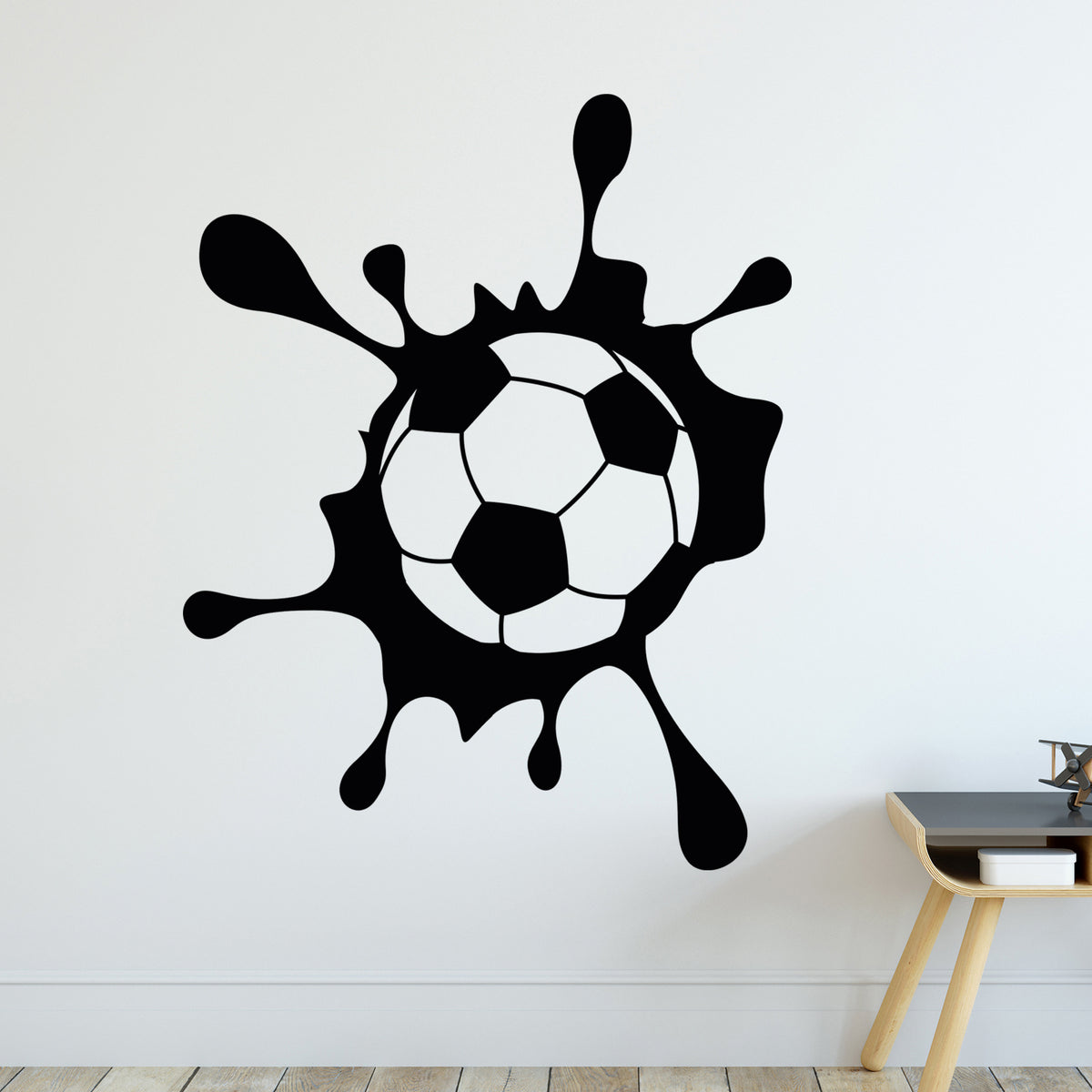 Wandtattoo mit Fußball in schwarzem Farbklecks an weißer Wand