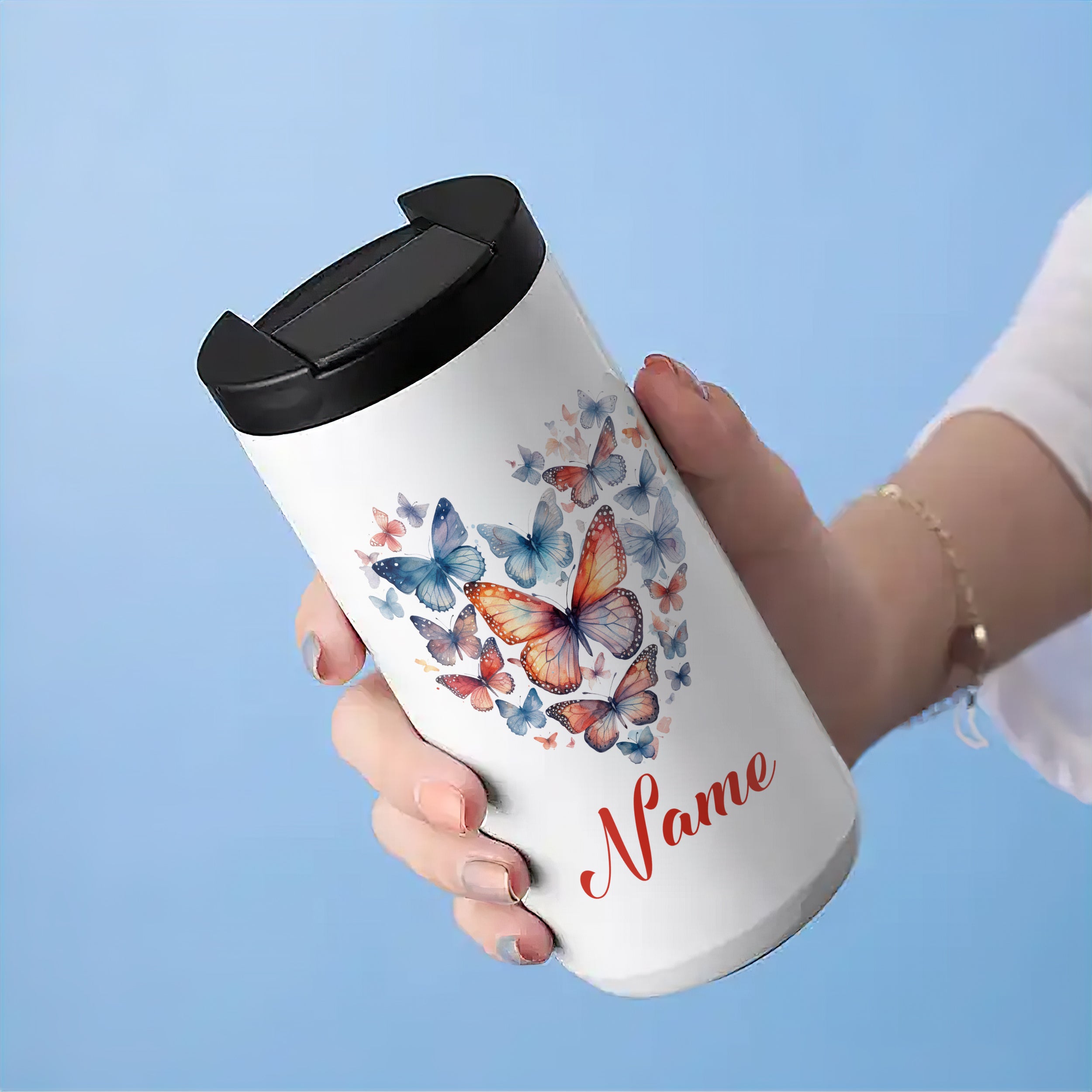 Weißer Thermobecher mit bunten Schmetterlingen und Namen.