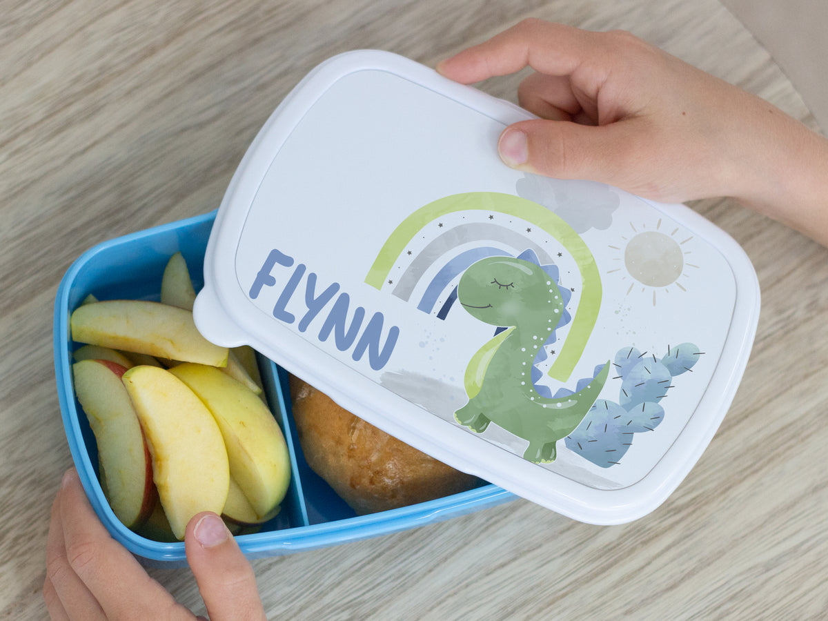 Bento-Box in Blau mit Dinosaurier-Motiv und Äpfeln.
