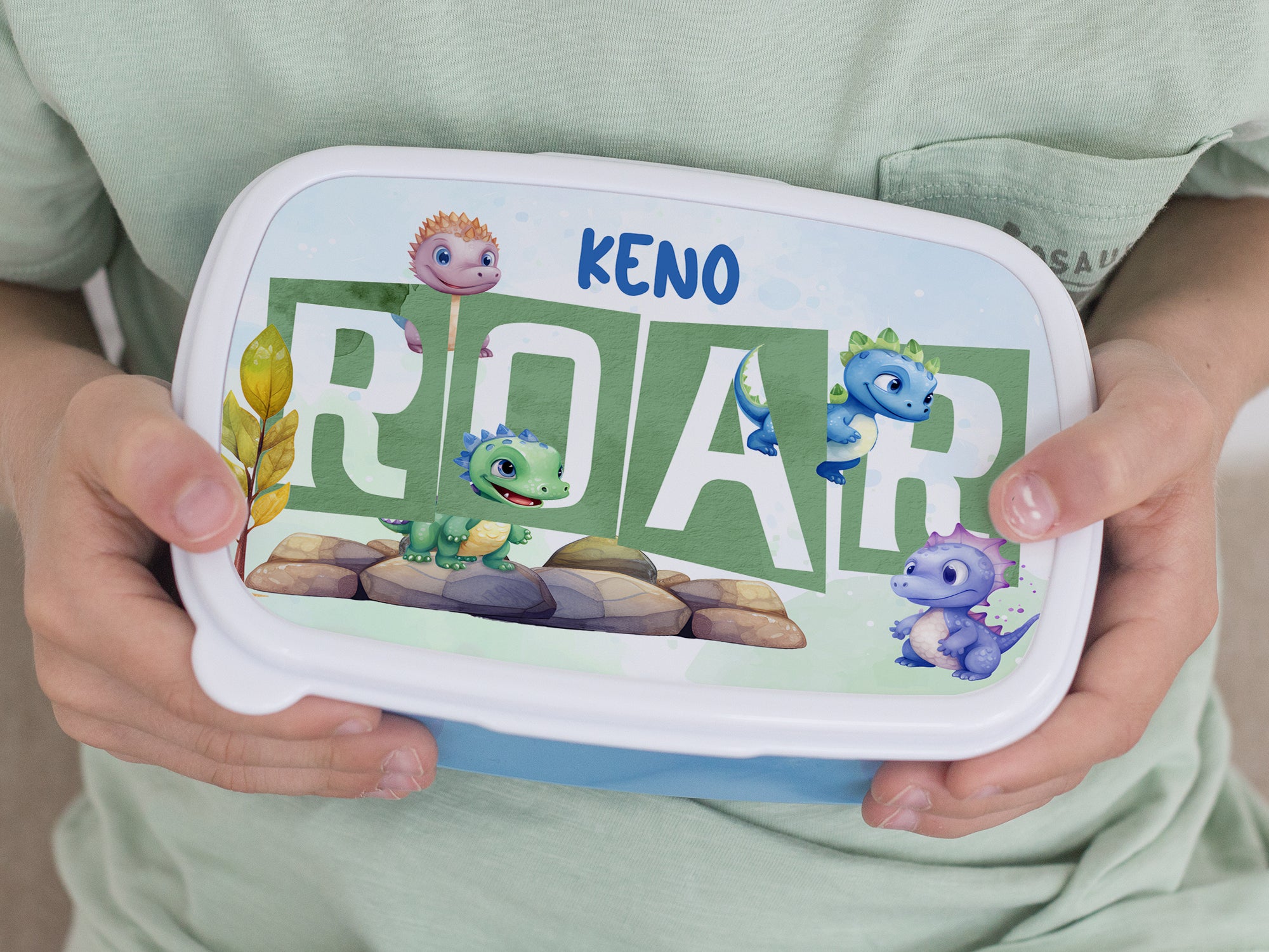 Bunte Brotdose mit Dinosaurier-Motiven und dem Wort "ROAR".