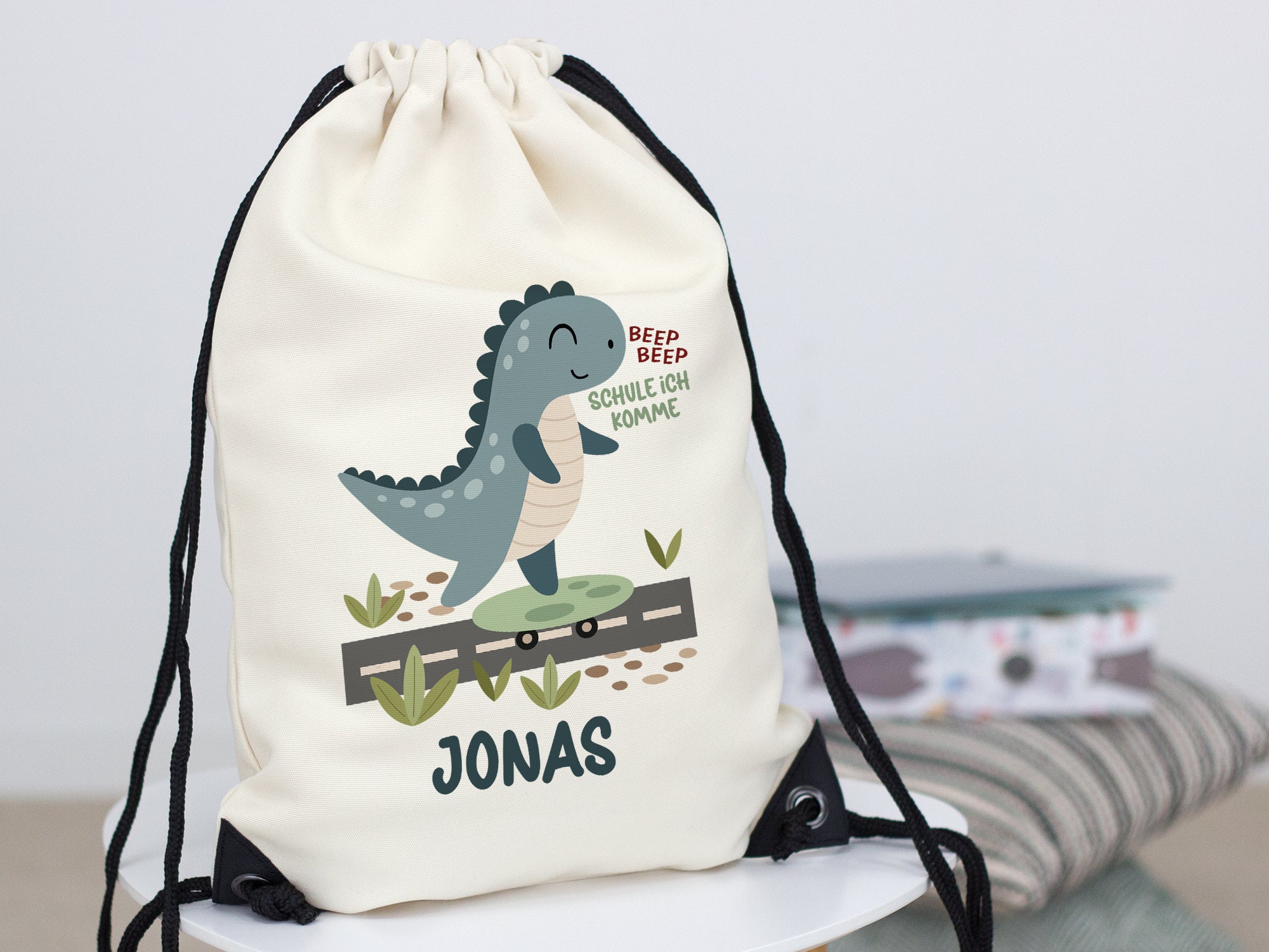 Beiger Turnbeutel mit Dinosaurier-Motiv und Namen "JONAS".