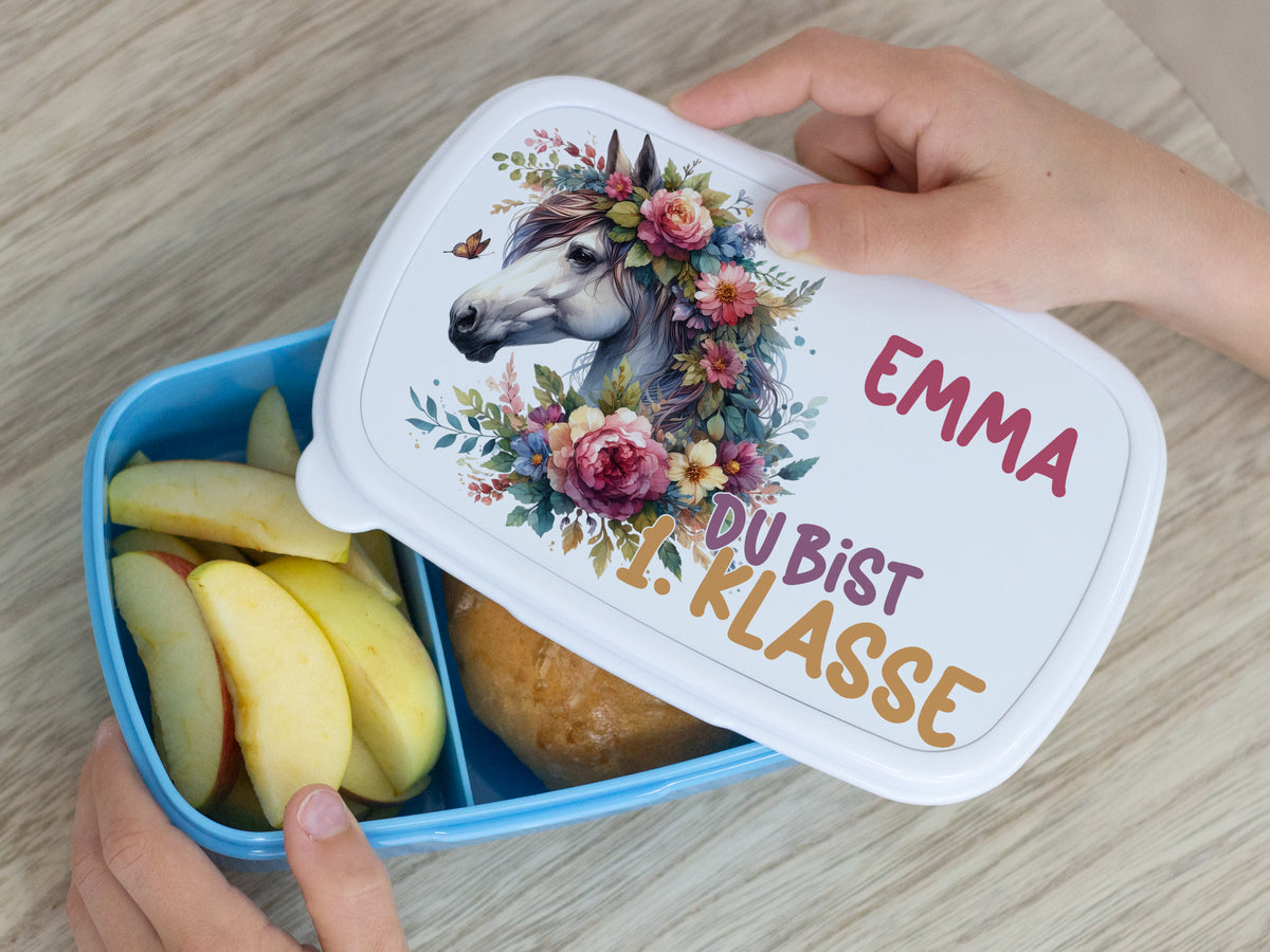 Bunte Brotdose mit Einhorn-Motiv, Äpfeln und Brötchen.