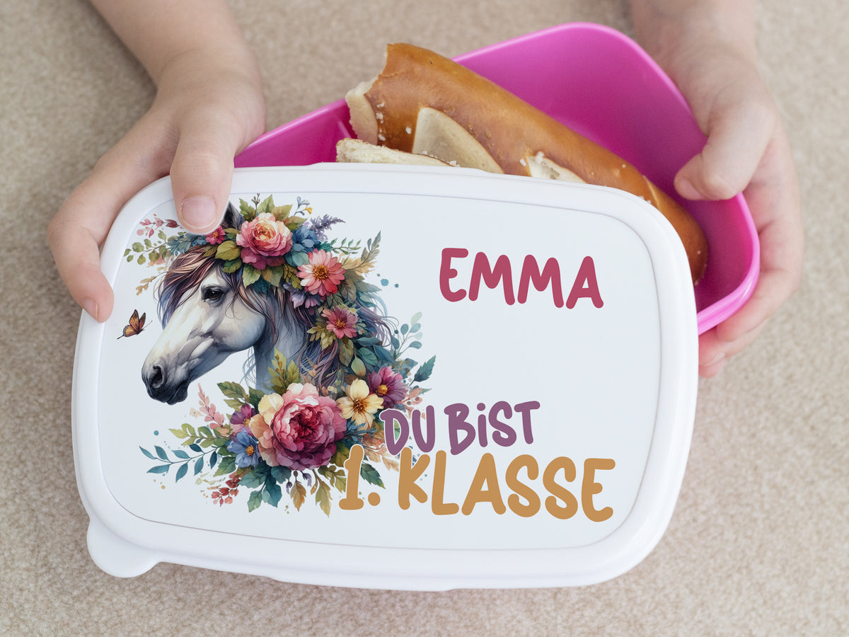 Bento-Box mit Einhorn-Motiv, rosa Blumen, weißer Hintergrund.