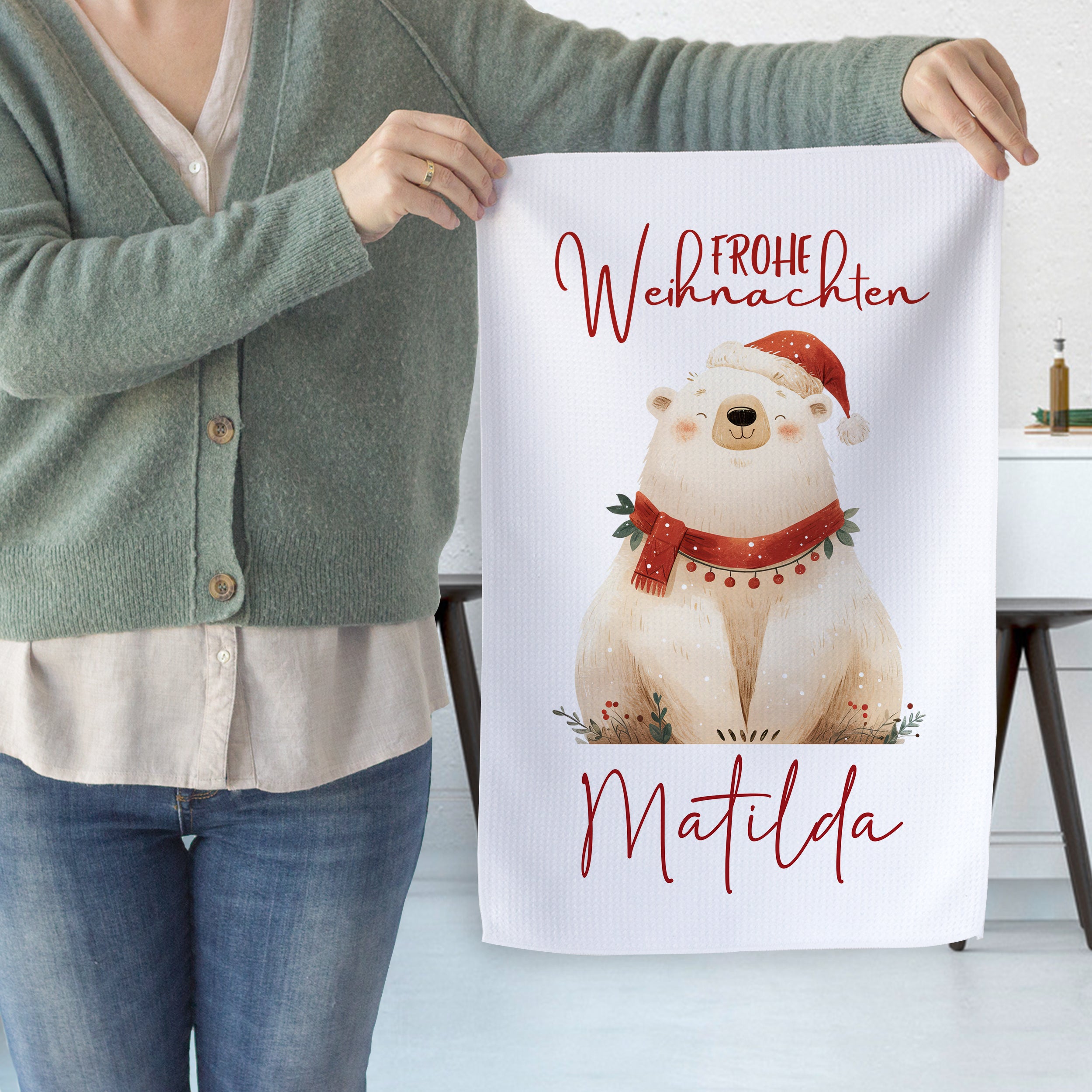 Weihnachtliches Geschirrtuch mit bäriger Illustration und rotem Text.