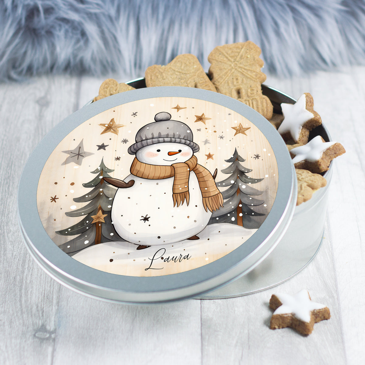 Kekse in runder Dose mit Schneemann-Motiv und Weihnachtsbaum.