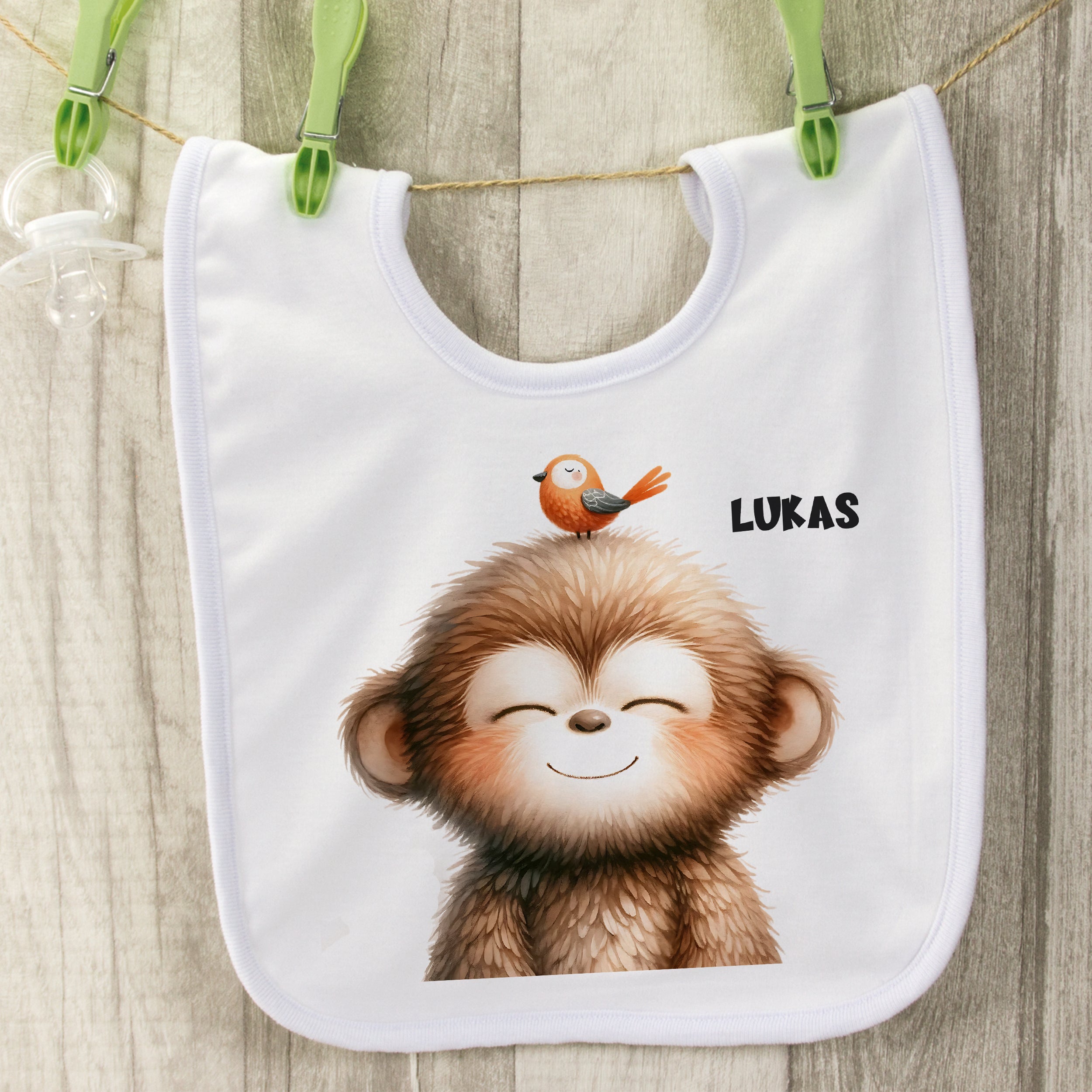 Weißes Lätzchen mit lächelndem Affen und Vogel, personalisiert.