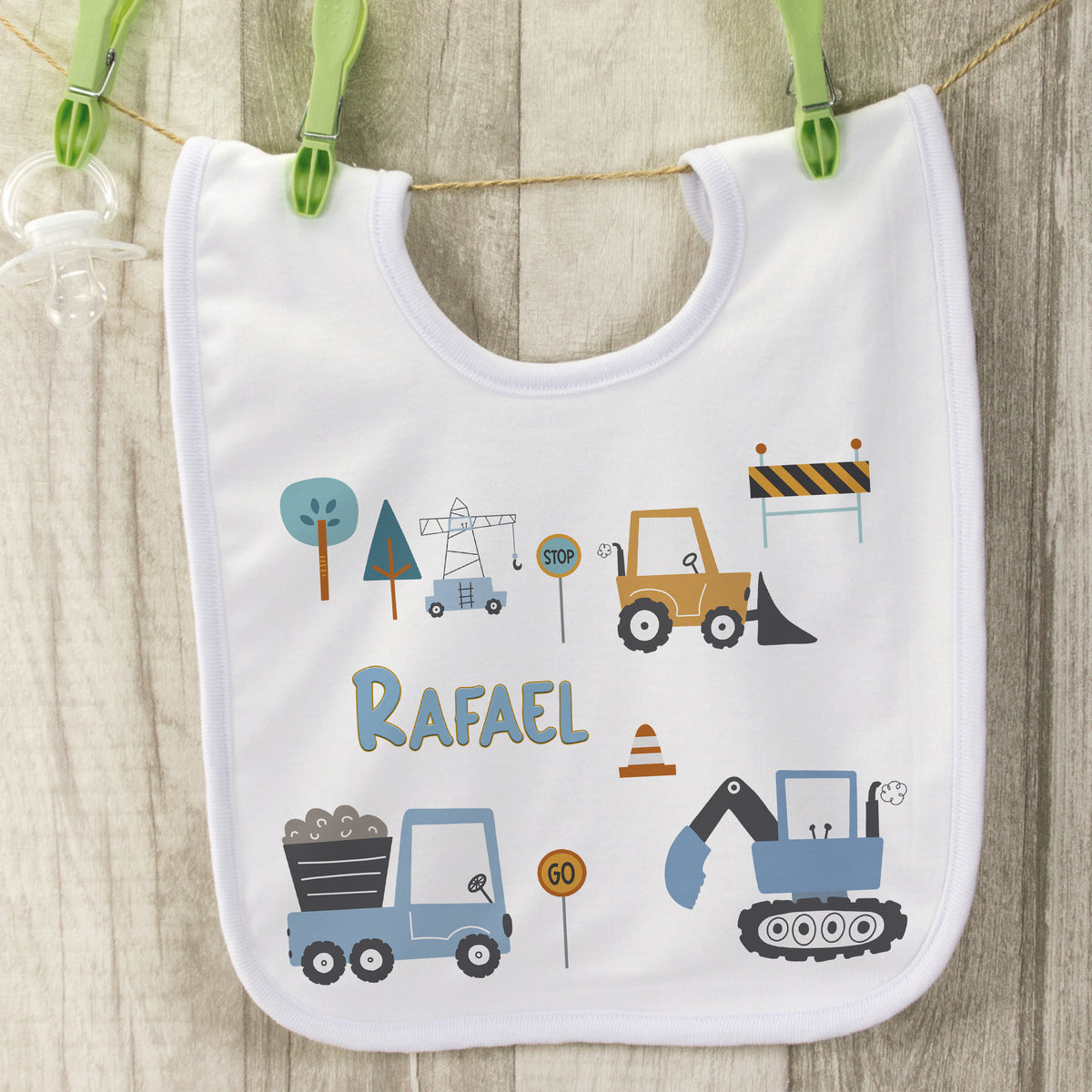 Weißes Lätzchen mit Baustellenmotiven und dem Namen Rafael.