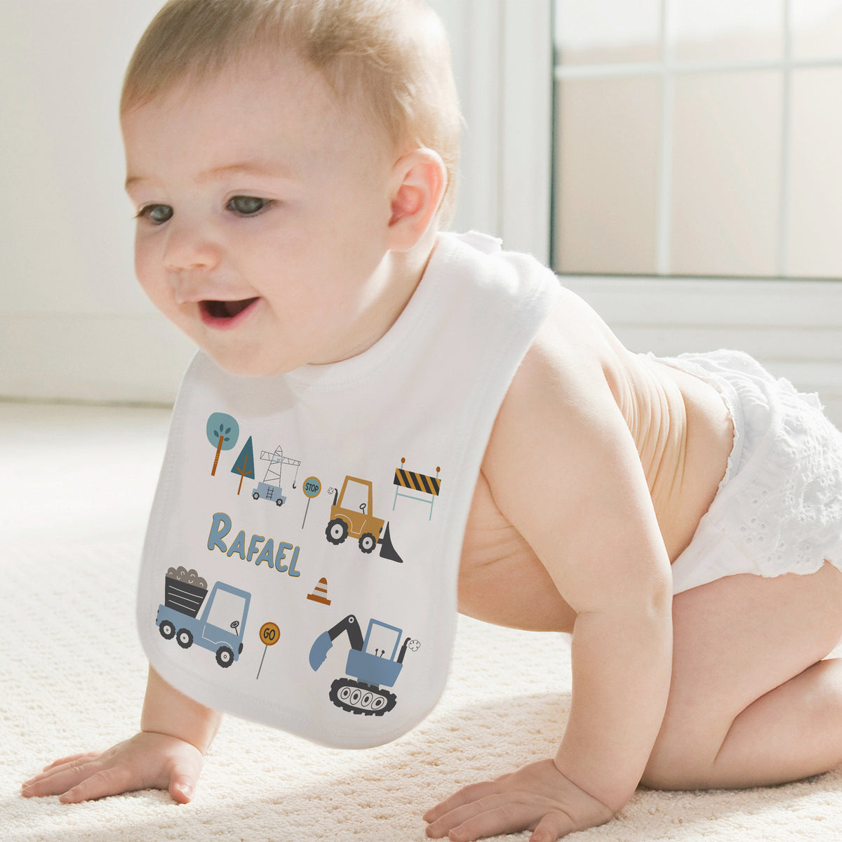 Baby mit Lätzchen, bunte Baustellenmotive und Name "Rafael".